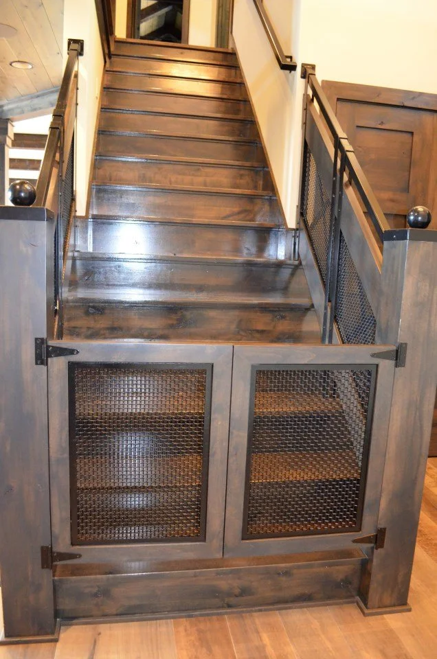 Wooden staircase with black metal mesh gates at the bottom, glass door at the top with gold trim, and a wooden wall on the right side.