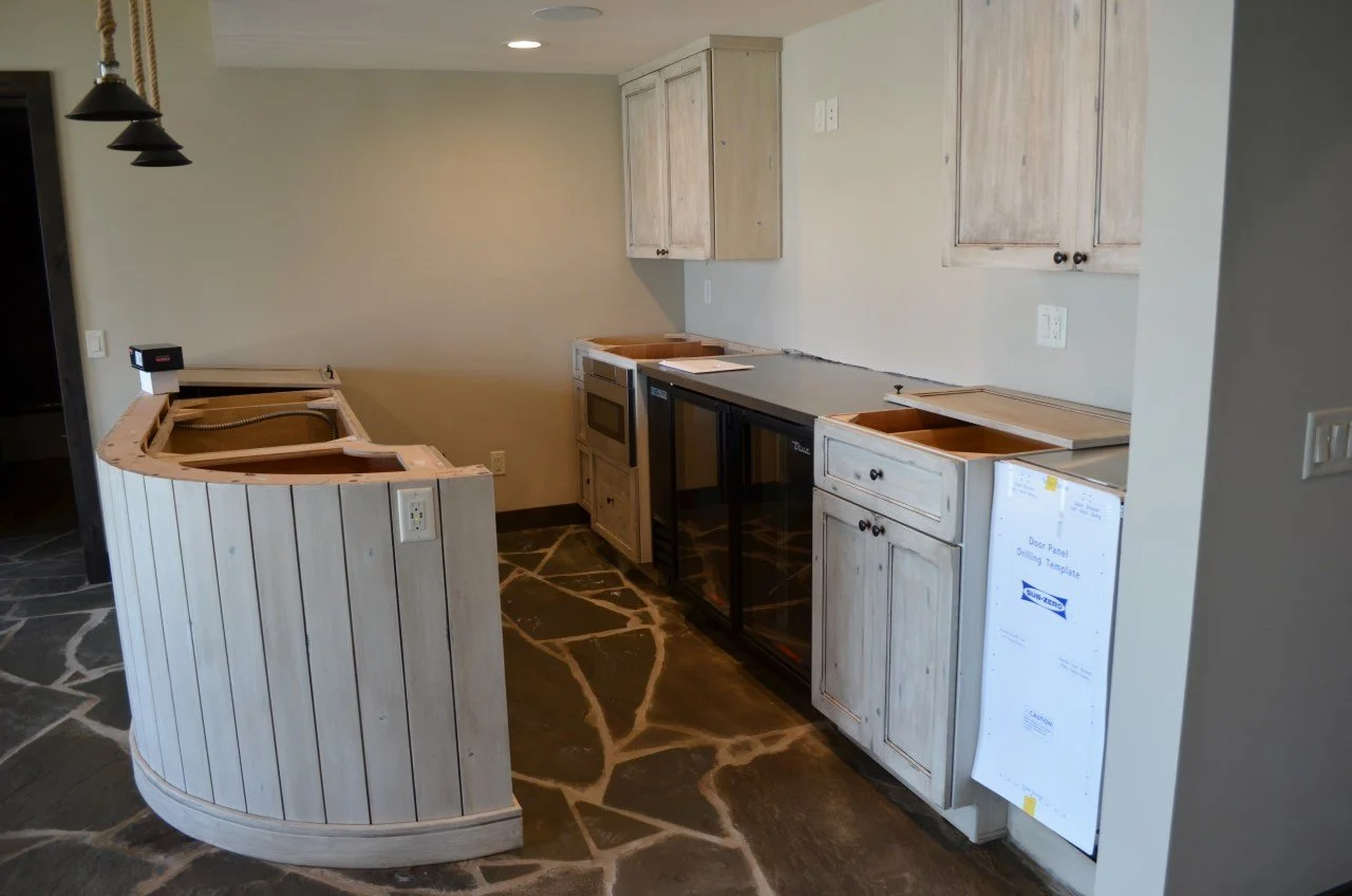 Kitchen area under construction with unfinished cabinets, a small countertop, and a stone floor.