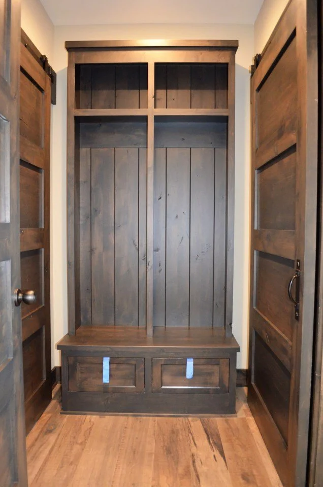 Empty wooden entryway with built-in storage and hooks for coats.