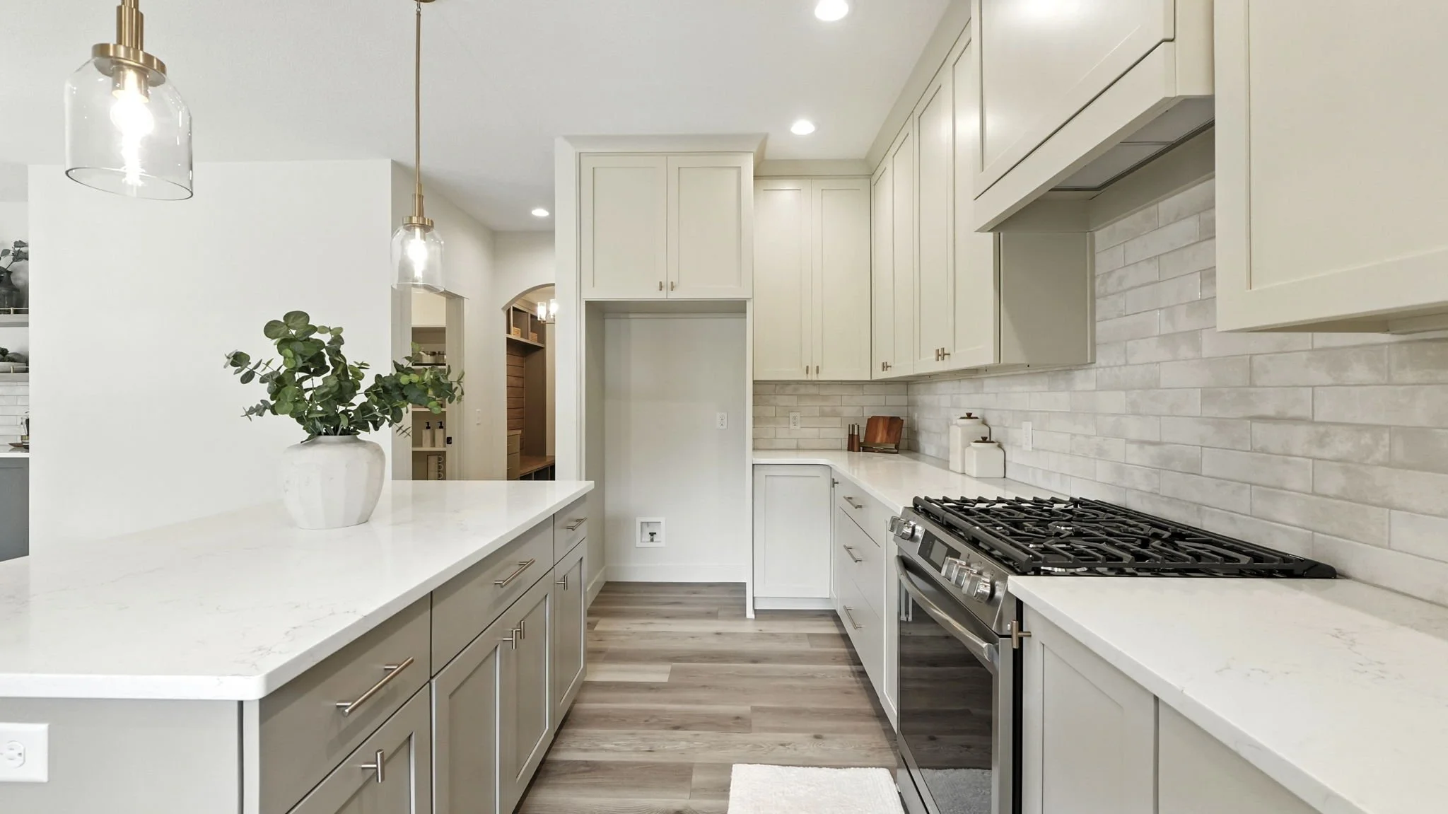 Modern kitchen with white cabinetry, light-colored countertops, a gas stove, and pendant lights.