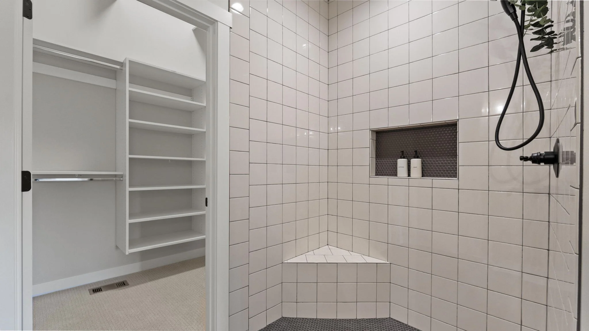 Bathroom shower area with pink square tiles, black handheld showerhead, and two bottles in the built-in shower niche; adjacent walk-in closet with white shelves and hanging rod.
