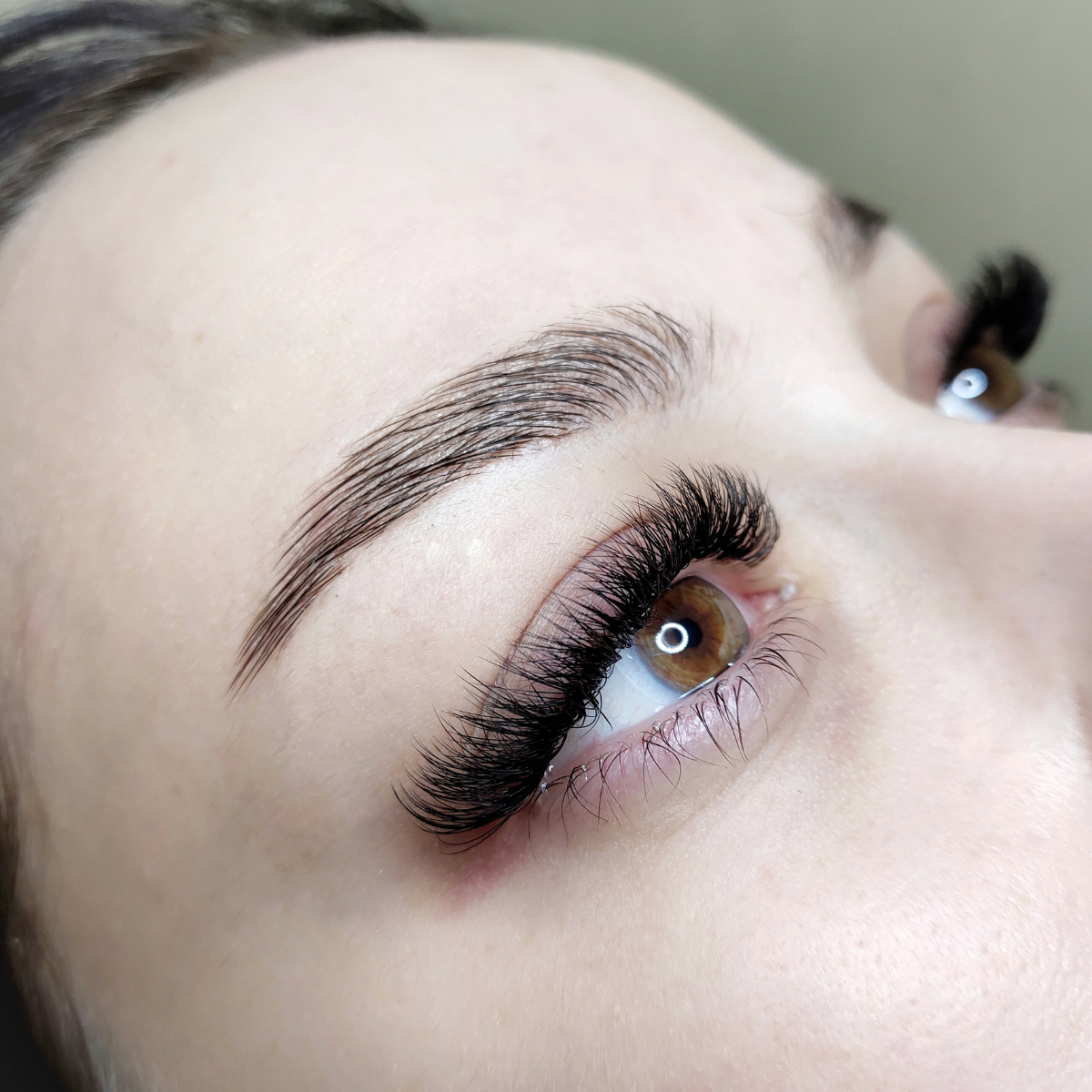 Cejas arregladas, pestañas postizas y ojos marrones de cerca.