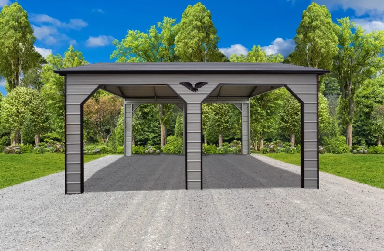 A metal carport with a black eagle decoration on the front center, set on a gravel driveway surrounded by lush green trees and shrubbery, under a bright blue sky with some clouds.