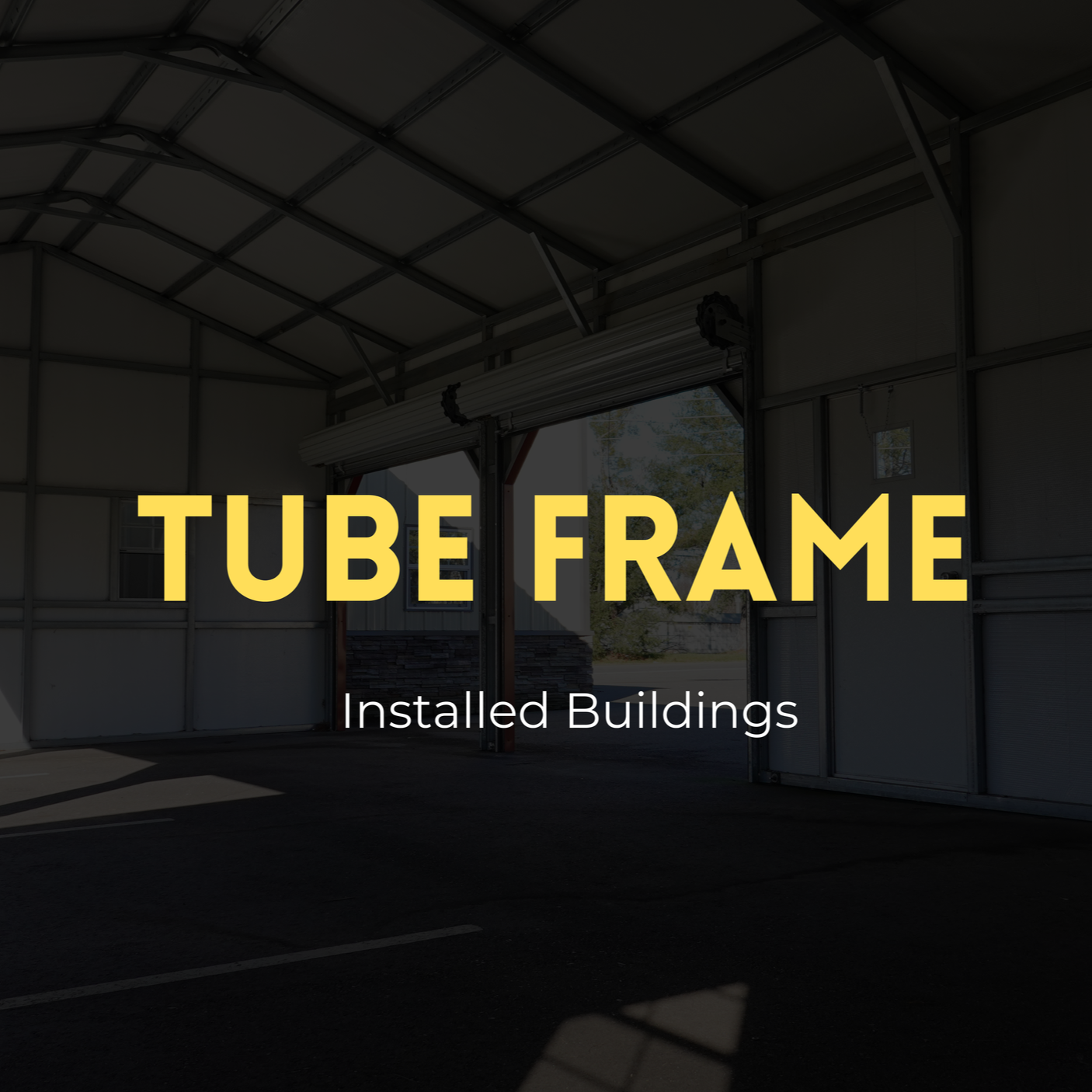 Interior of a metal building with a large open garage door, with overlaid text 'TUBE FRAME' and 'Installed Buildings'.