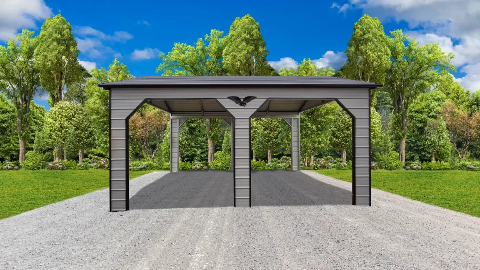 Gray metal carport with two bays, situated on a gravel driveway, surrounded by green trees and grass under a partly cloudy bright blue sky.