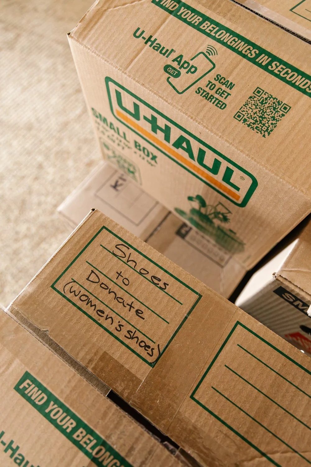 Boxes filled with donatable items stacked by a wall in a house