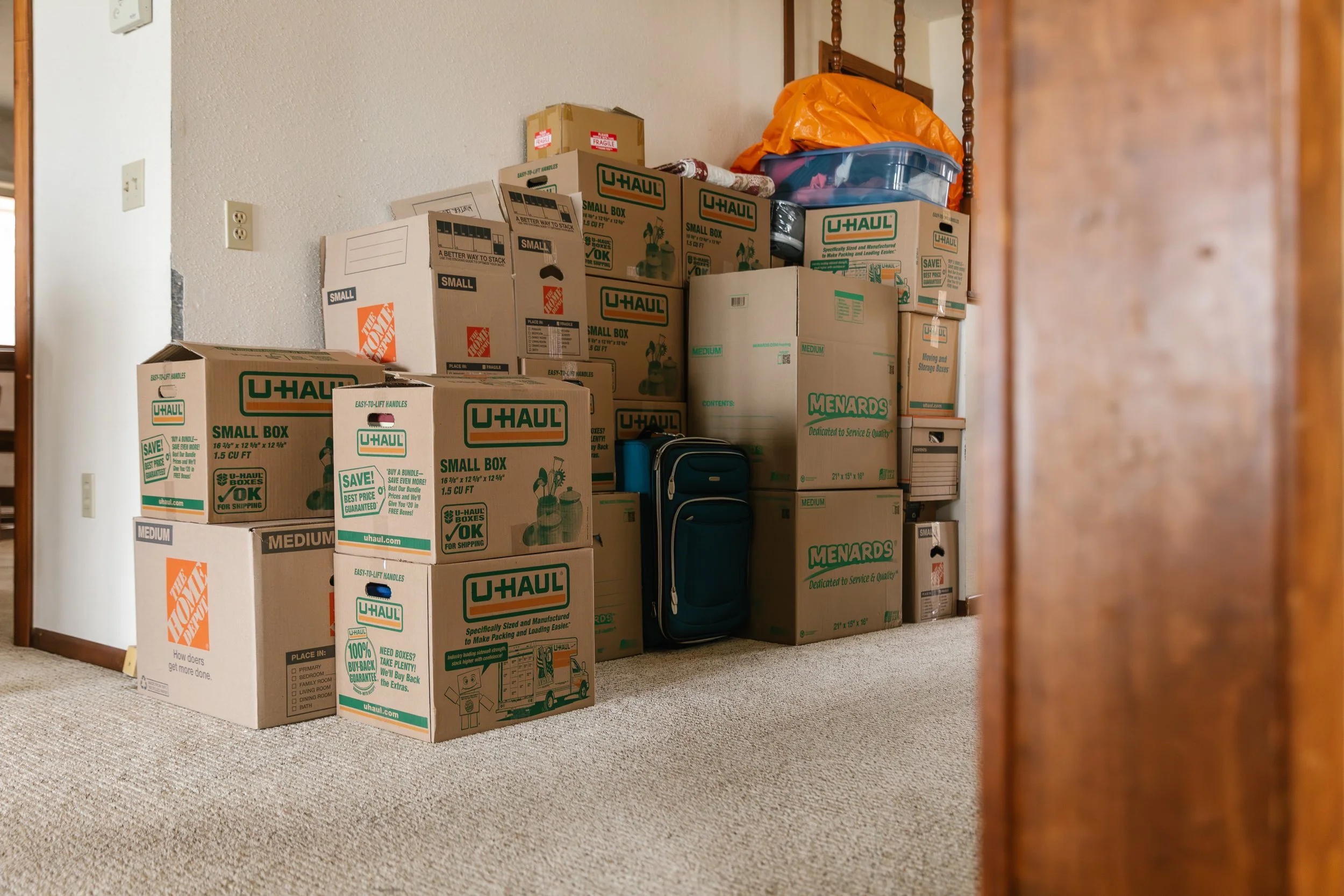 Carboard boxes packed and stacked next to a wall in a home