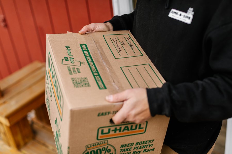 Man carrying a box of donation items out of a home
