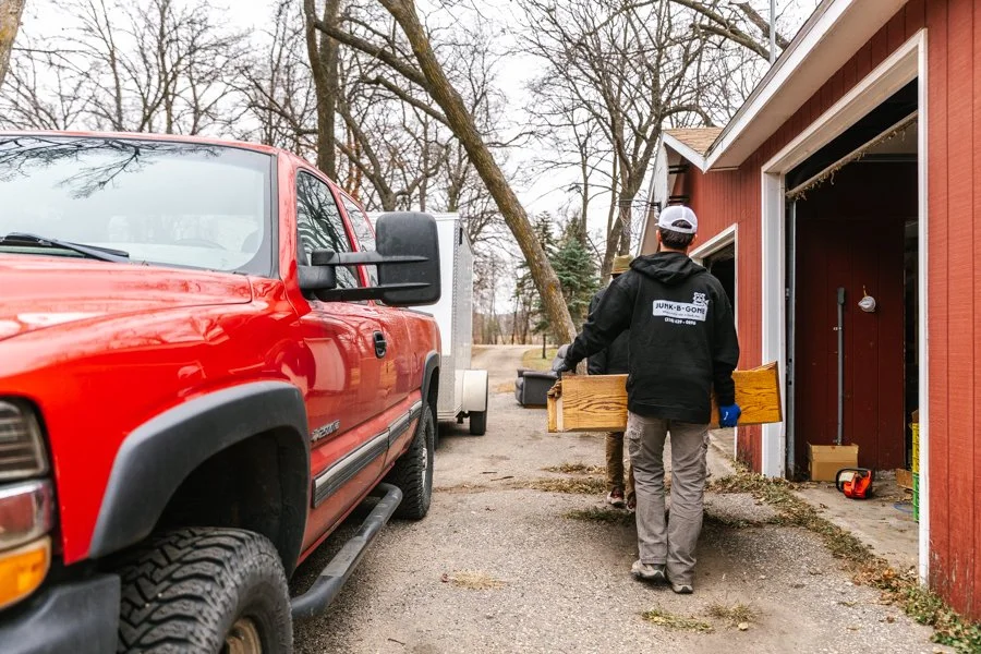 Two junk removal experts hauling a wooden bookshelf to a trailer