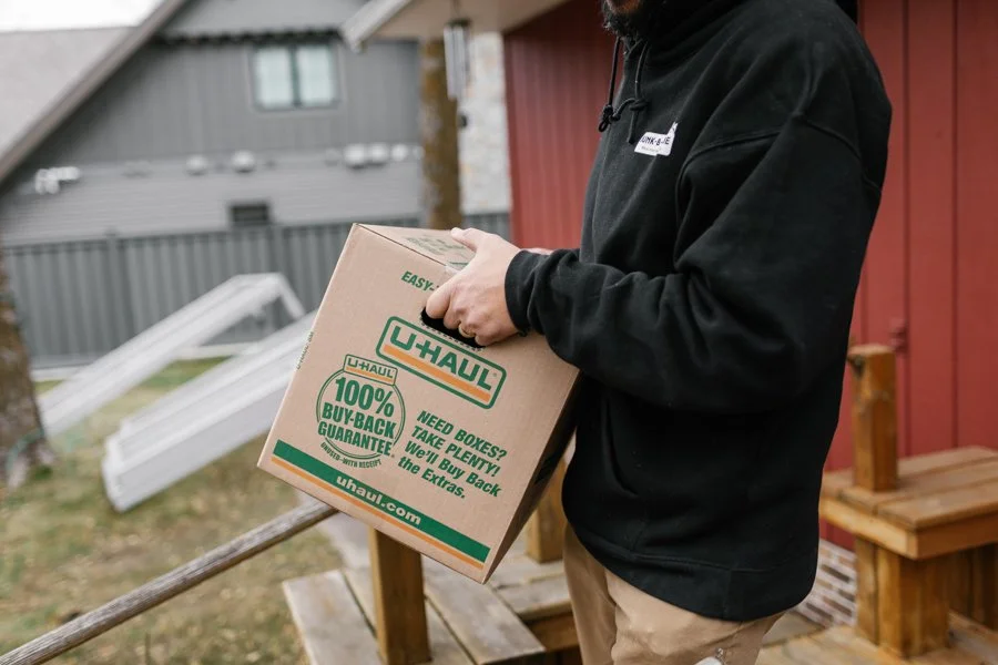 man carrying a cardboard box out of a home