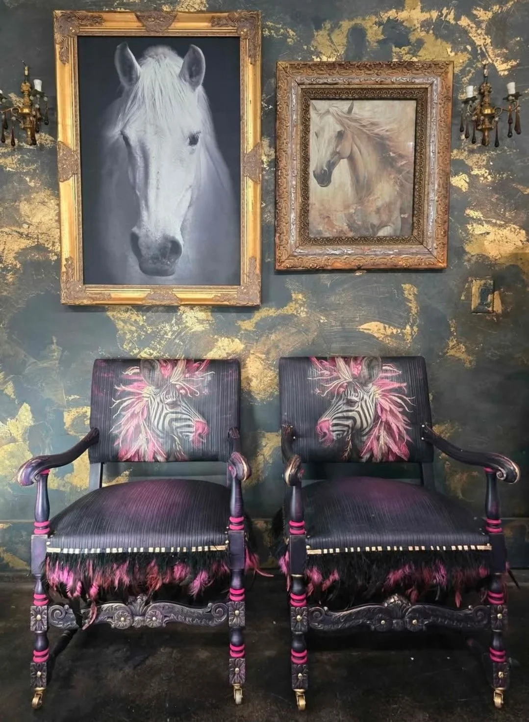 Two chairs with zebra and feather designs on the backrests and fur trim on the seats, placed in front of a dark, textured wall with gold accents. Above begins two framed horse portraits, one in black and white and the other in sepia tones, both with 