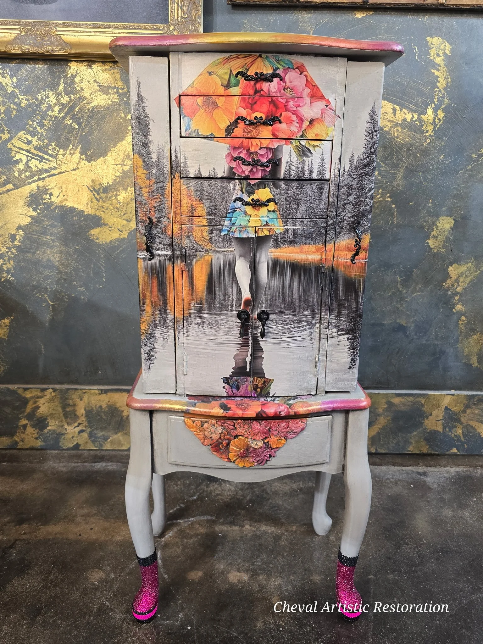 An ornate dresser painted with a scenic landscape of a woman walking with an umbrella in a floral dress, reflected in a lake, surrounded by trees and a sunset sky. The dresser has floral and landscape motifs, with the woman's legs and umbrella promin