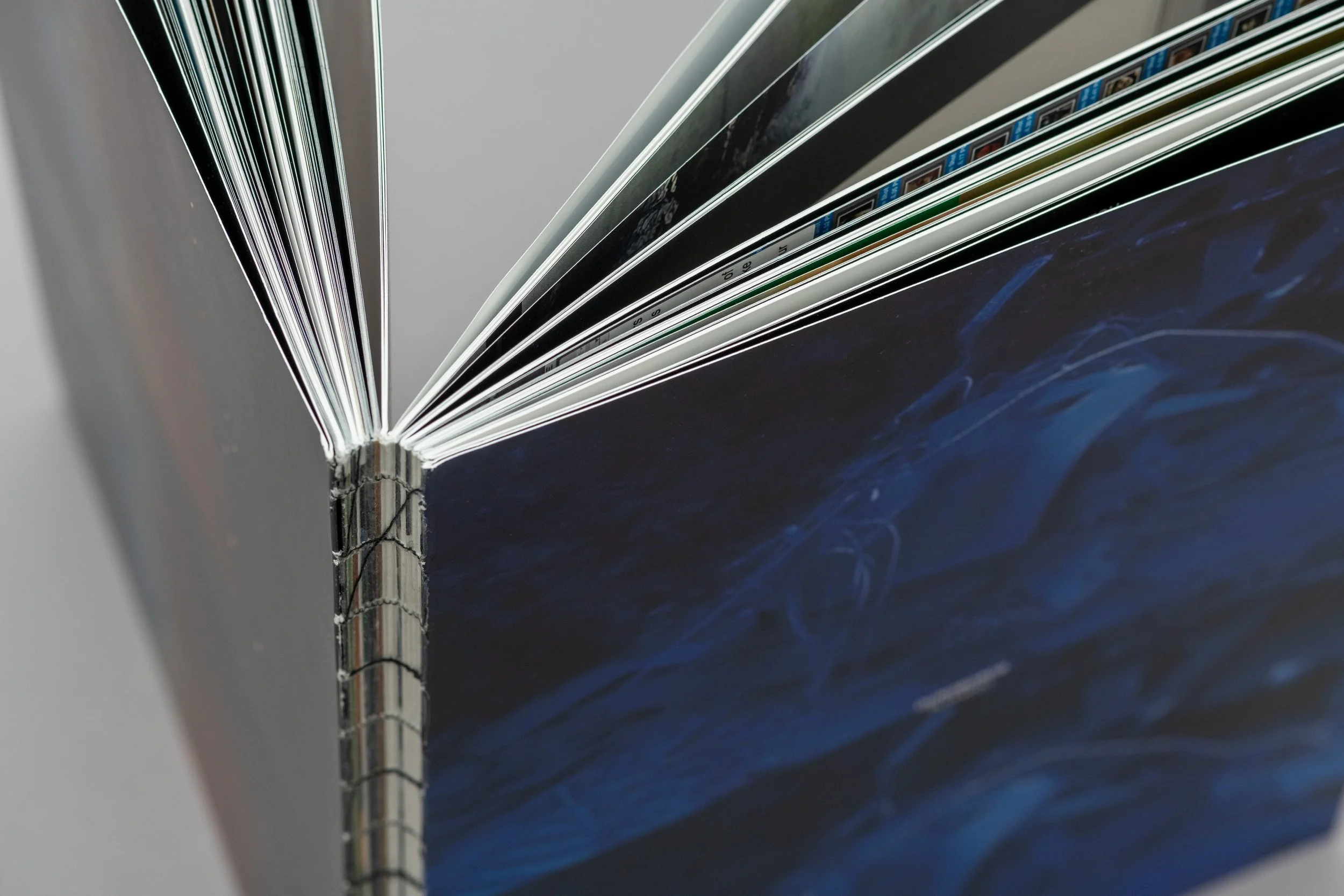 Angolo di un libro con pagine incollate e copertina rigida, visibile la pagina con immagini e testo.