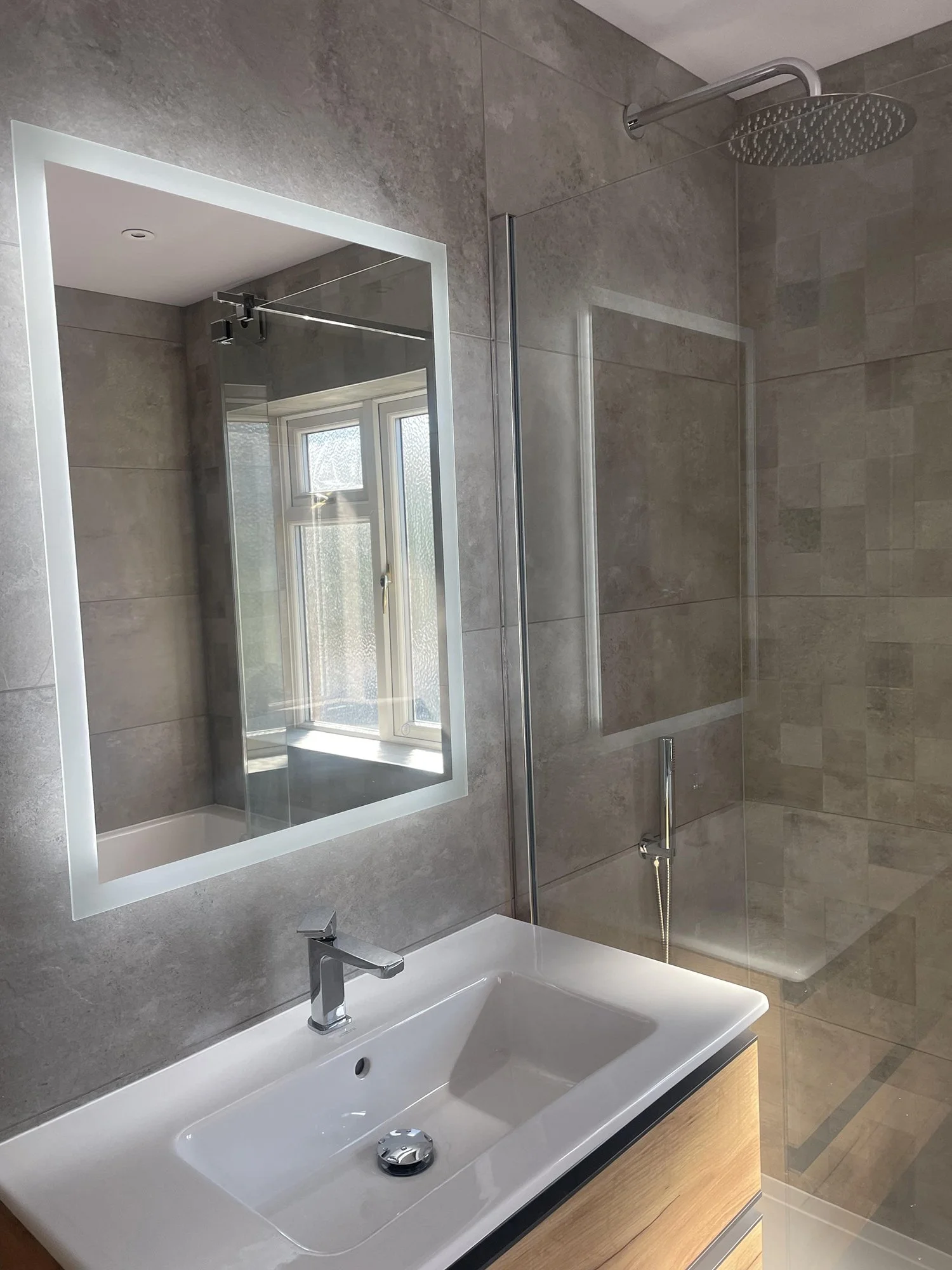 Modern bathroom with a white sink, mirror, and a glass-enclosed shower.