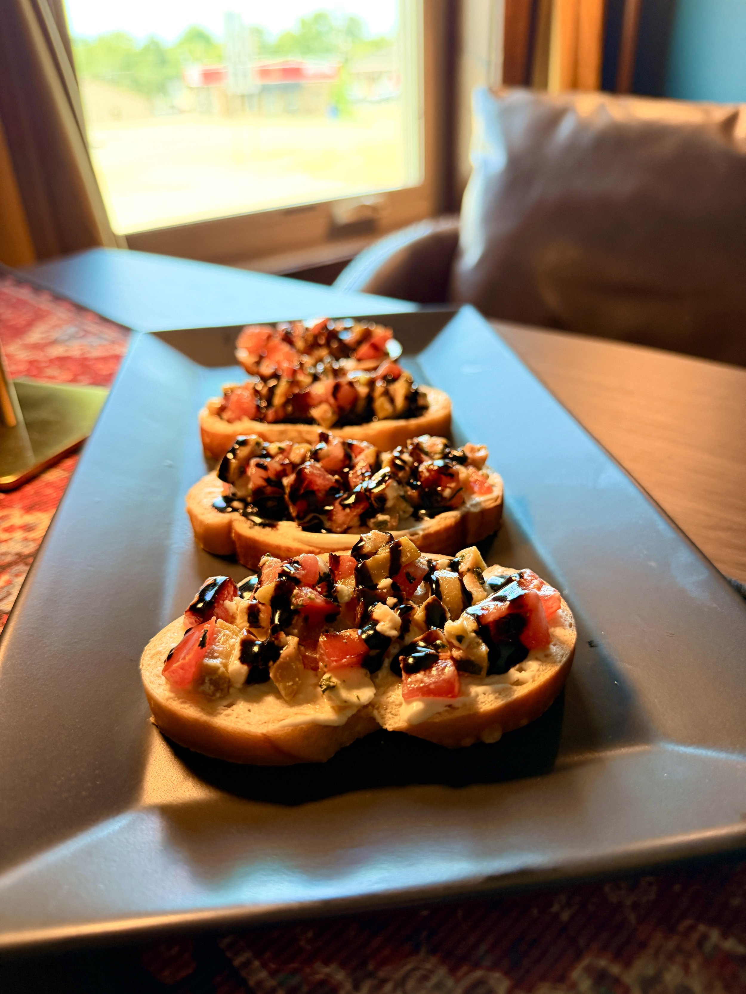 Three pieces of toast topped with chopped vegetables and drizzled with balsamic glaze, placed on a blue tray.