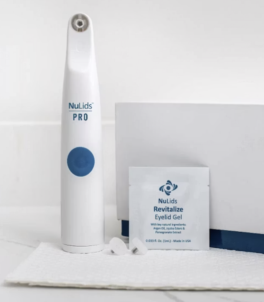 NuLids PRO oral irrigator, NuLids Revitalize Eyelid Gel, and small white capsules on a white towel