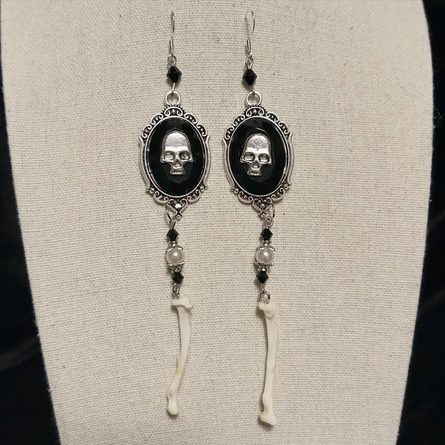 These earrings feature silver skull cameos with upcycled faux pearls and dazzling black glass beads.