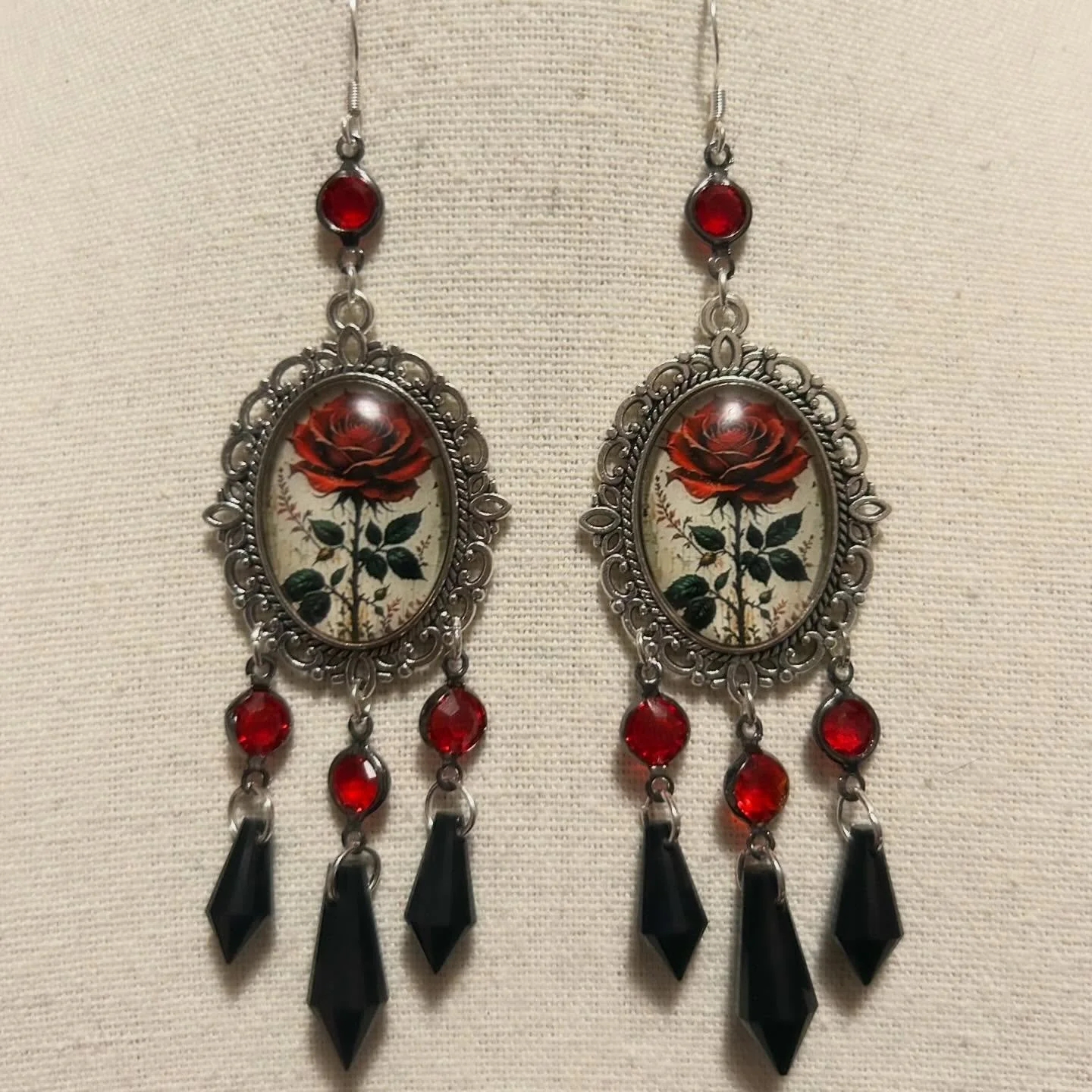 Pretty roses inside cameo-like frames. The are combined with red crystals and black glass pendants.