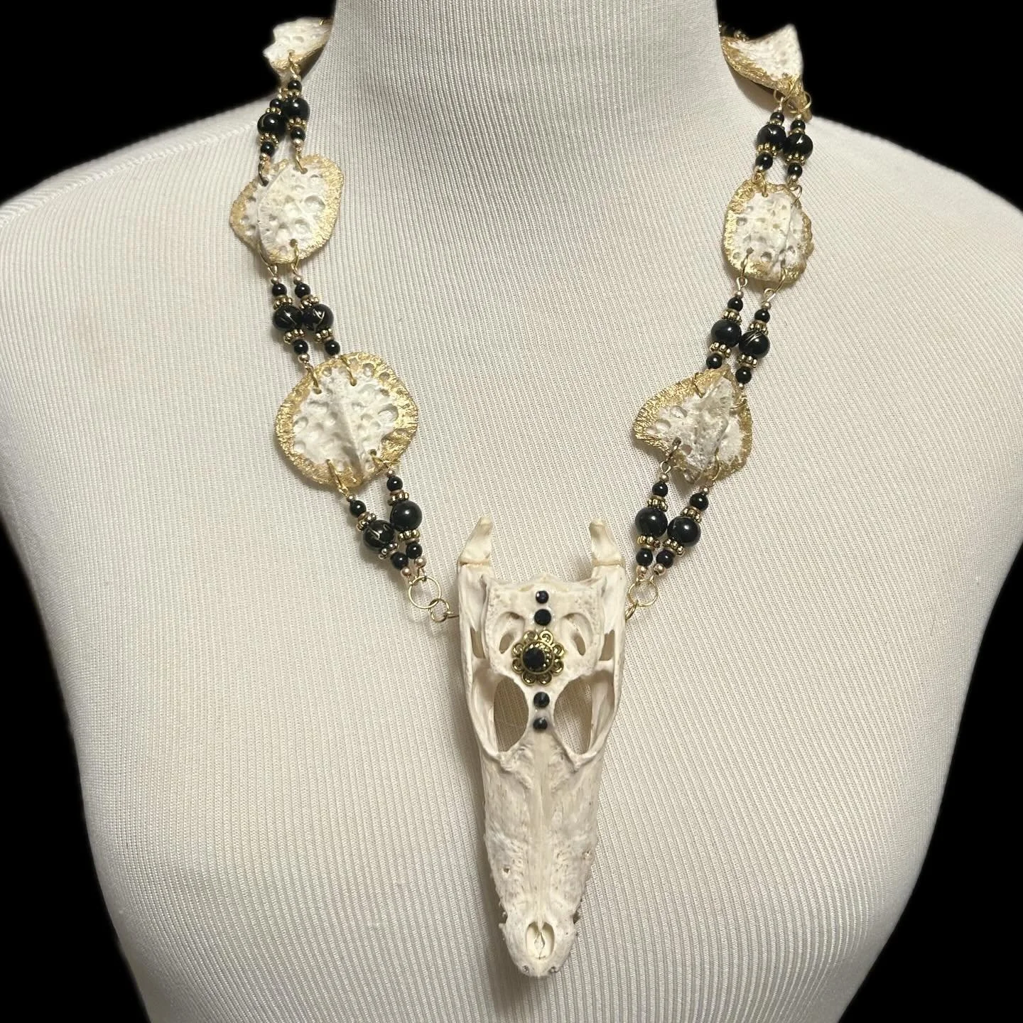 This necklace has a small alligator head with gold leafed scute and black and gold beads.