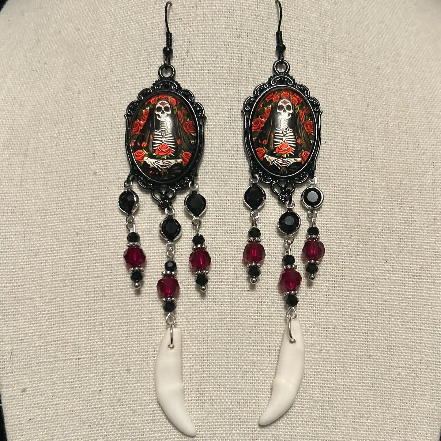 Santa Muertos cabochons with repurposed beads and coyote fangs.