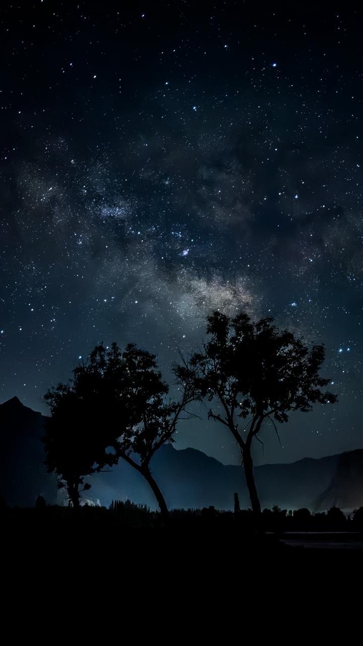 A clear night sky filled with countless stars and the Milky Way galaxy stretching vertically through the center.