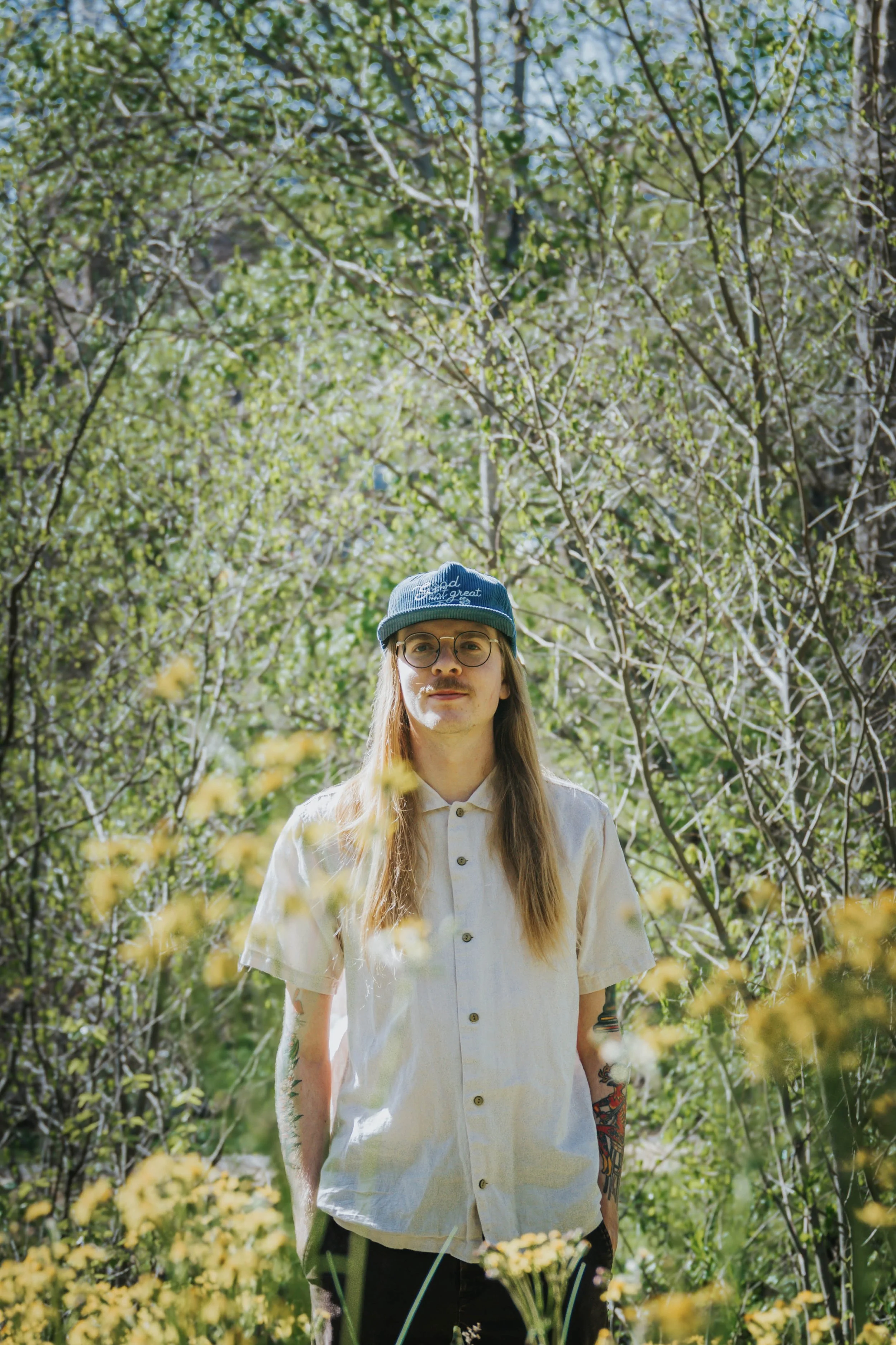 Lua Flora stands in a field surrounded by flowers and trees.