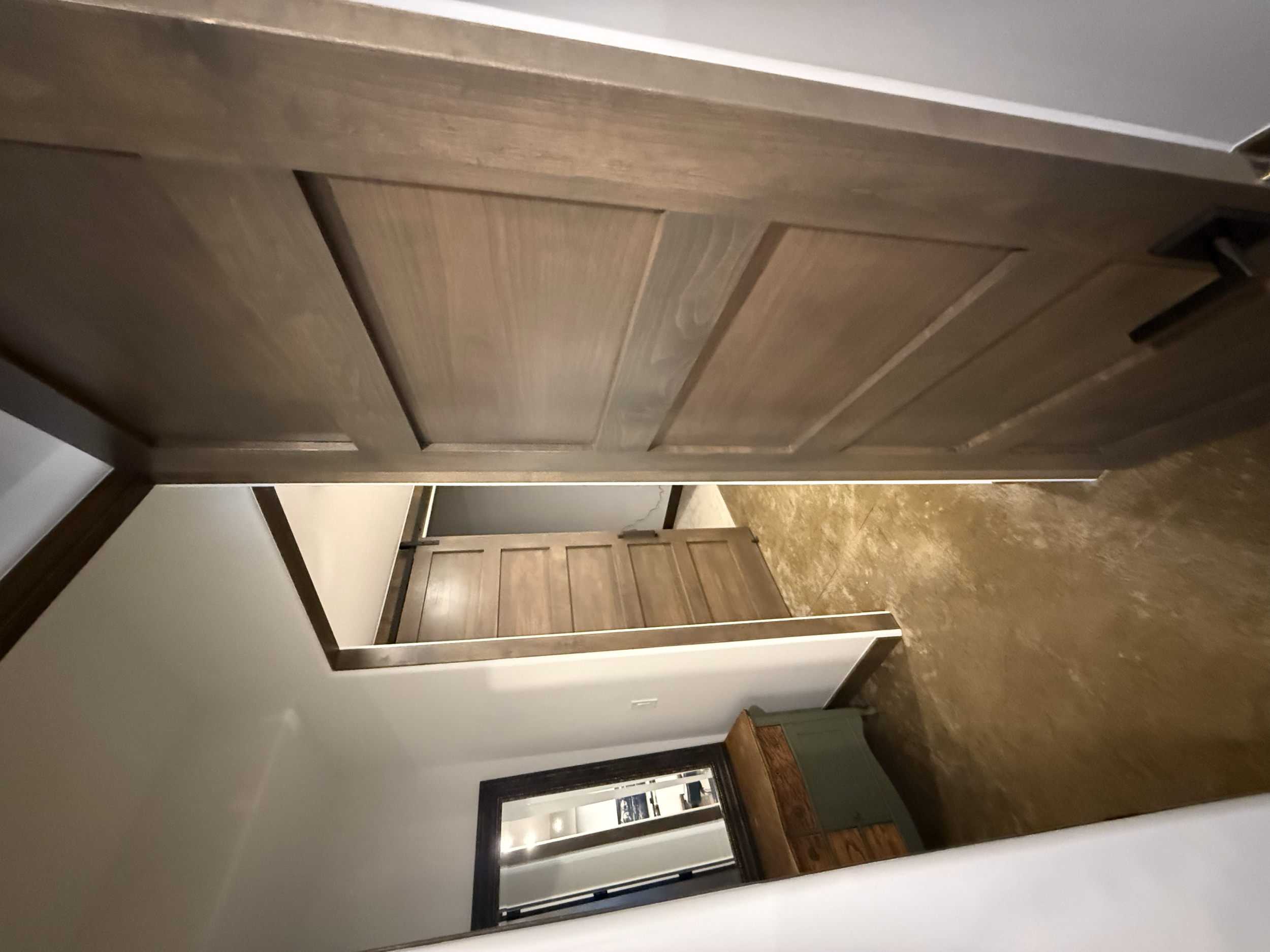 Interior view of a room showing two open wooden doors, a dresser, and a window with a dark frame.