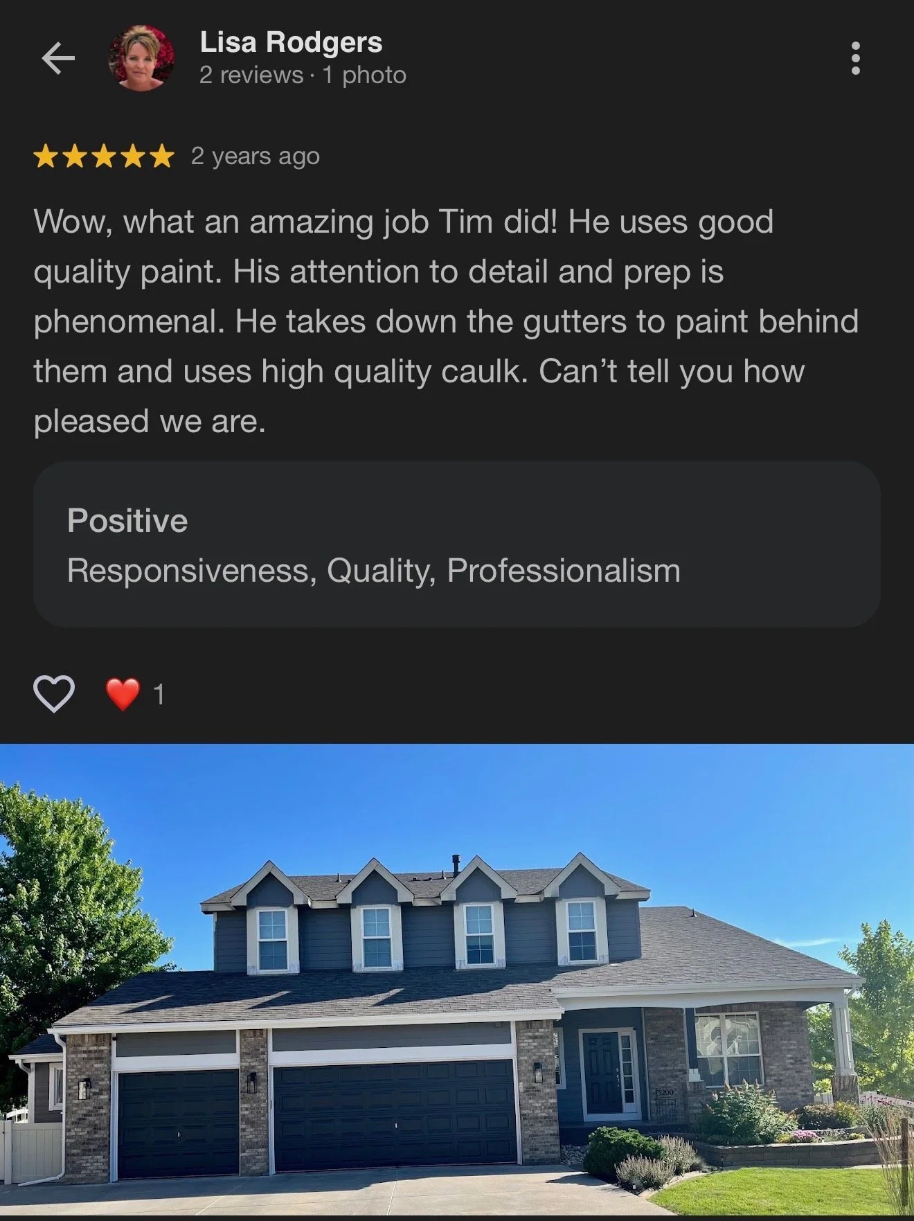 A modern two-story house with a gray and brick exterior, three dormer windows on the roof, a large double garage, and a well-maintained front yard with a green lawn and shrubs.