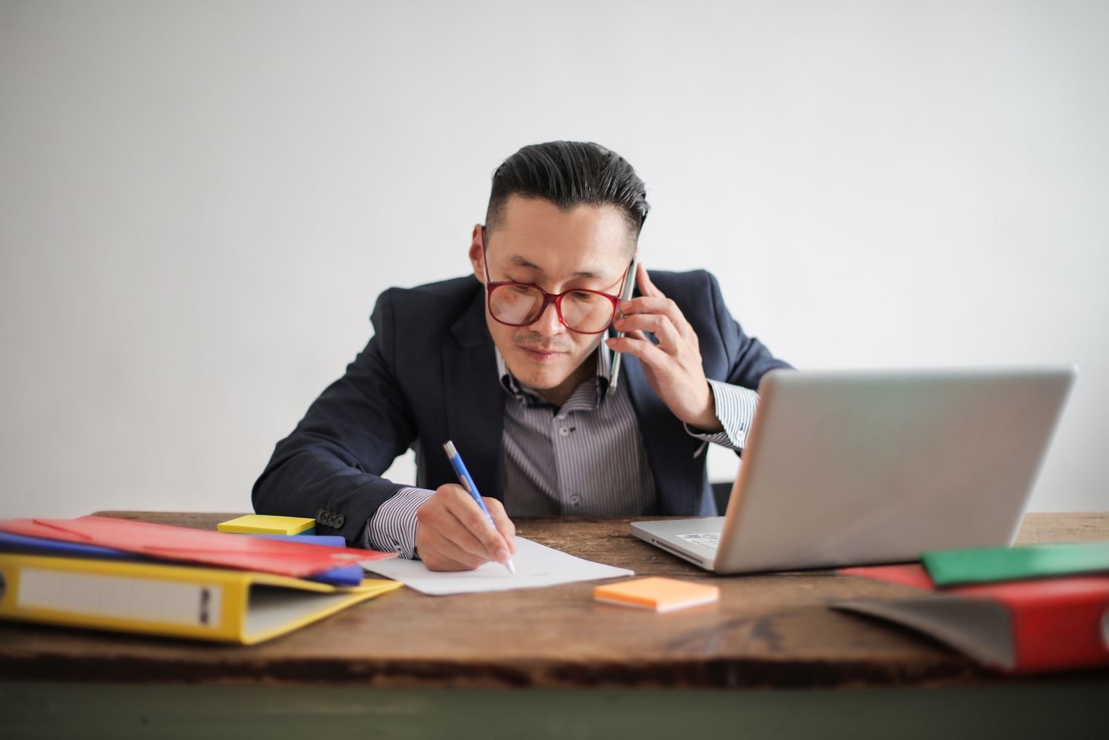 Salesperson making a follow-up call and taking notes at his desk