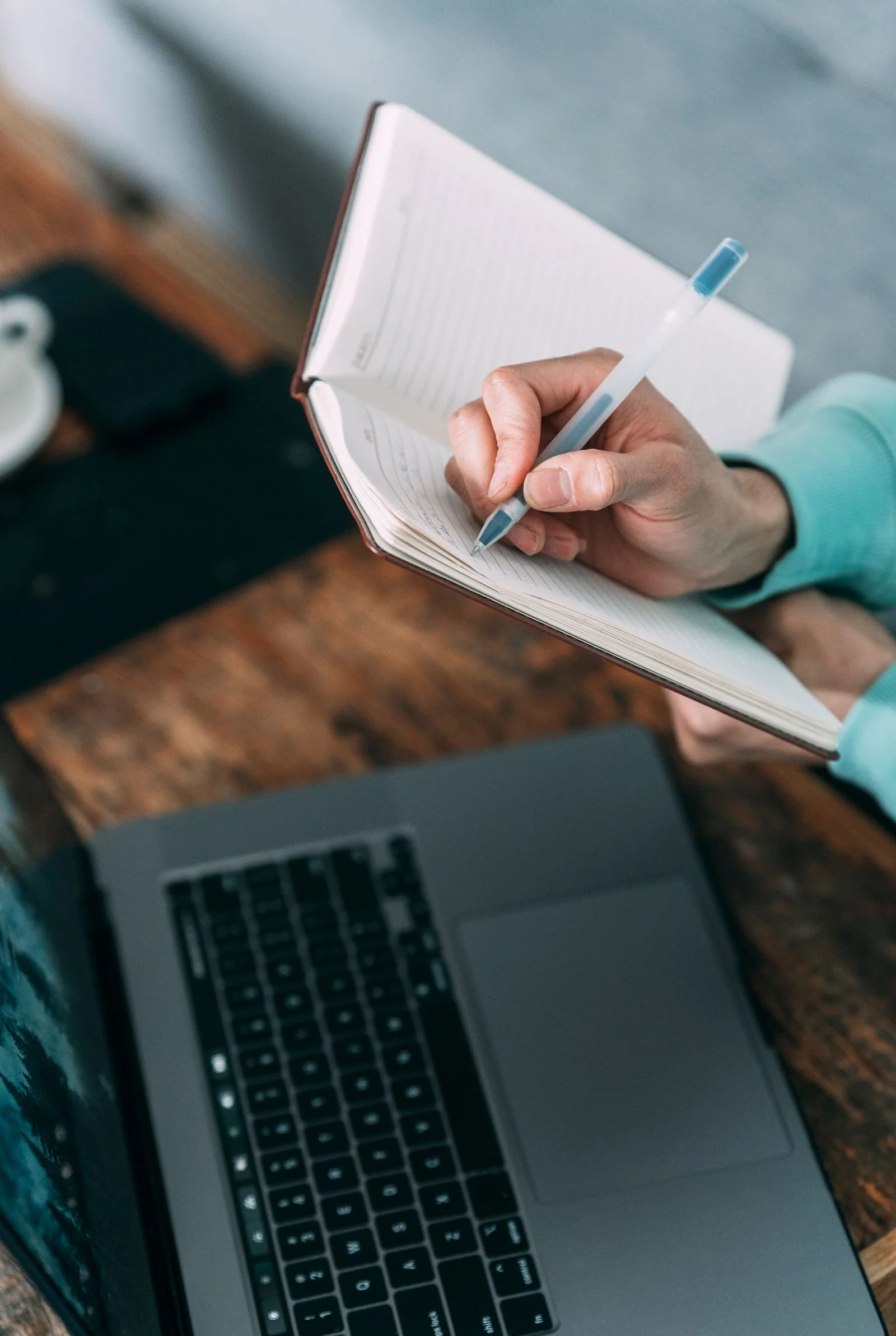 Planning follow-up touches in a notebook beside a laptop