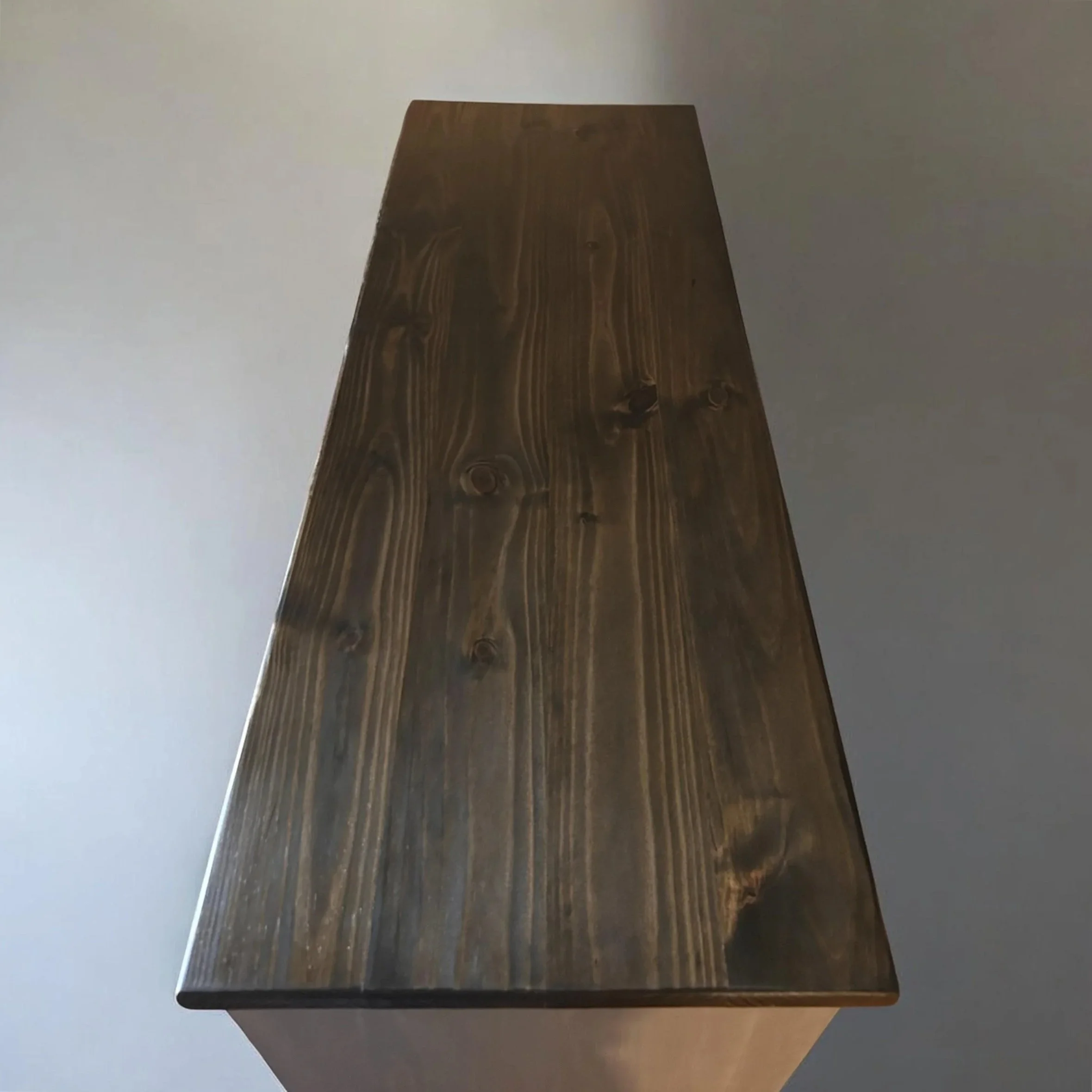 This Hearthside Console pairs a richly toned wood top with a clean, architectural base. Designed to sit comfortably beside a fireplace or within a refined living space, it offers both presence and purpose without excess. The deep, hand-finished surfa
