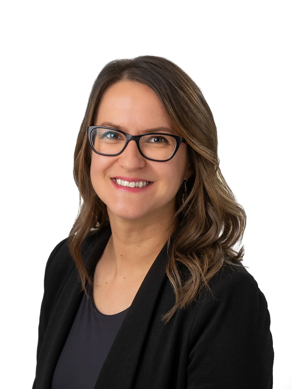 A woman with shoulder-length brown hair, wearing glasses, a black blazer, and a dark top, smiling against a white background.
