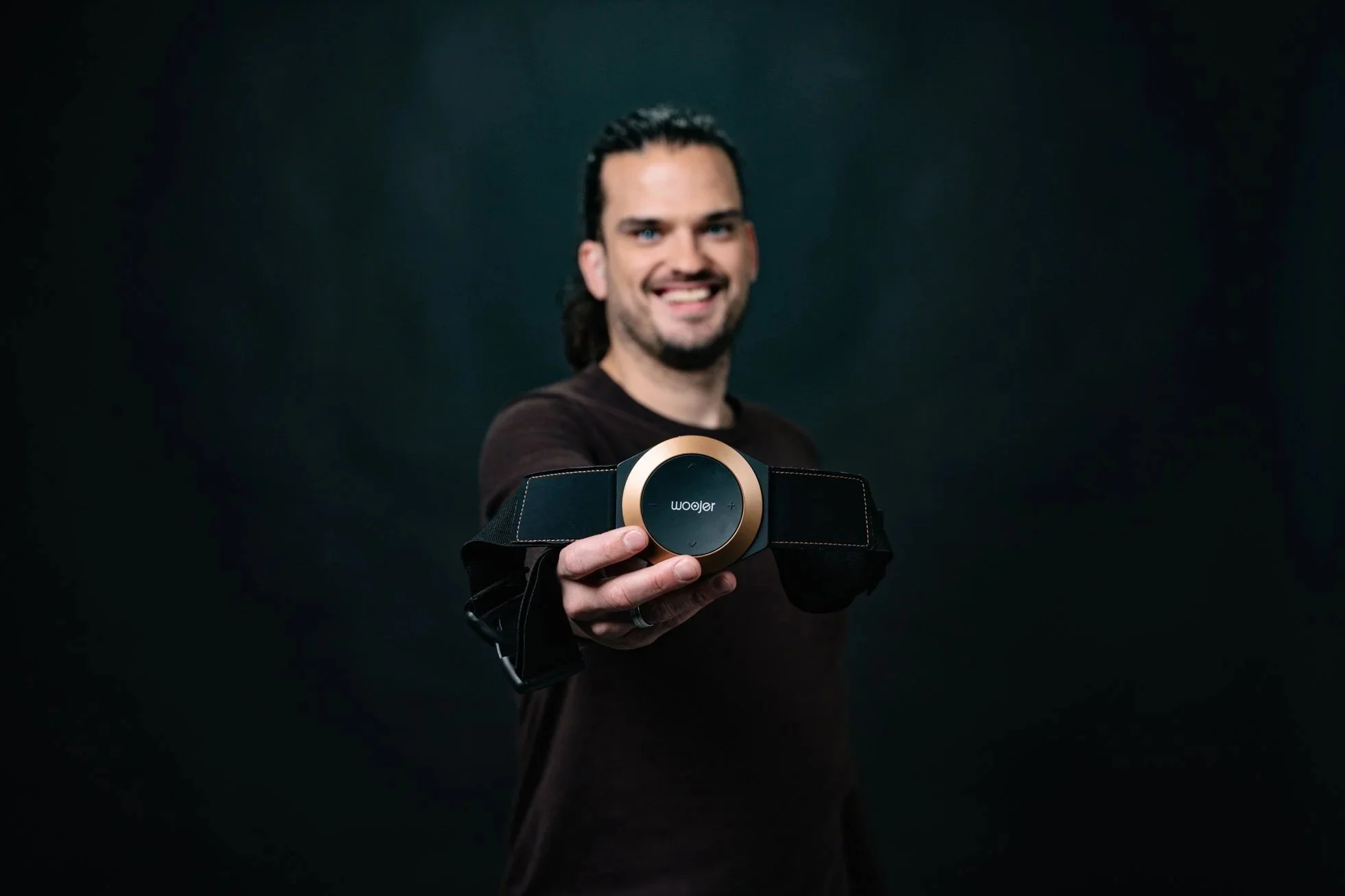 Man smiling and holding a futuristic device or gadget towards the camera.