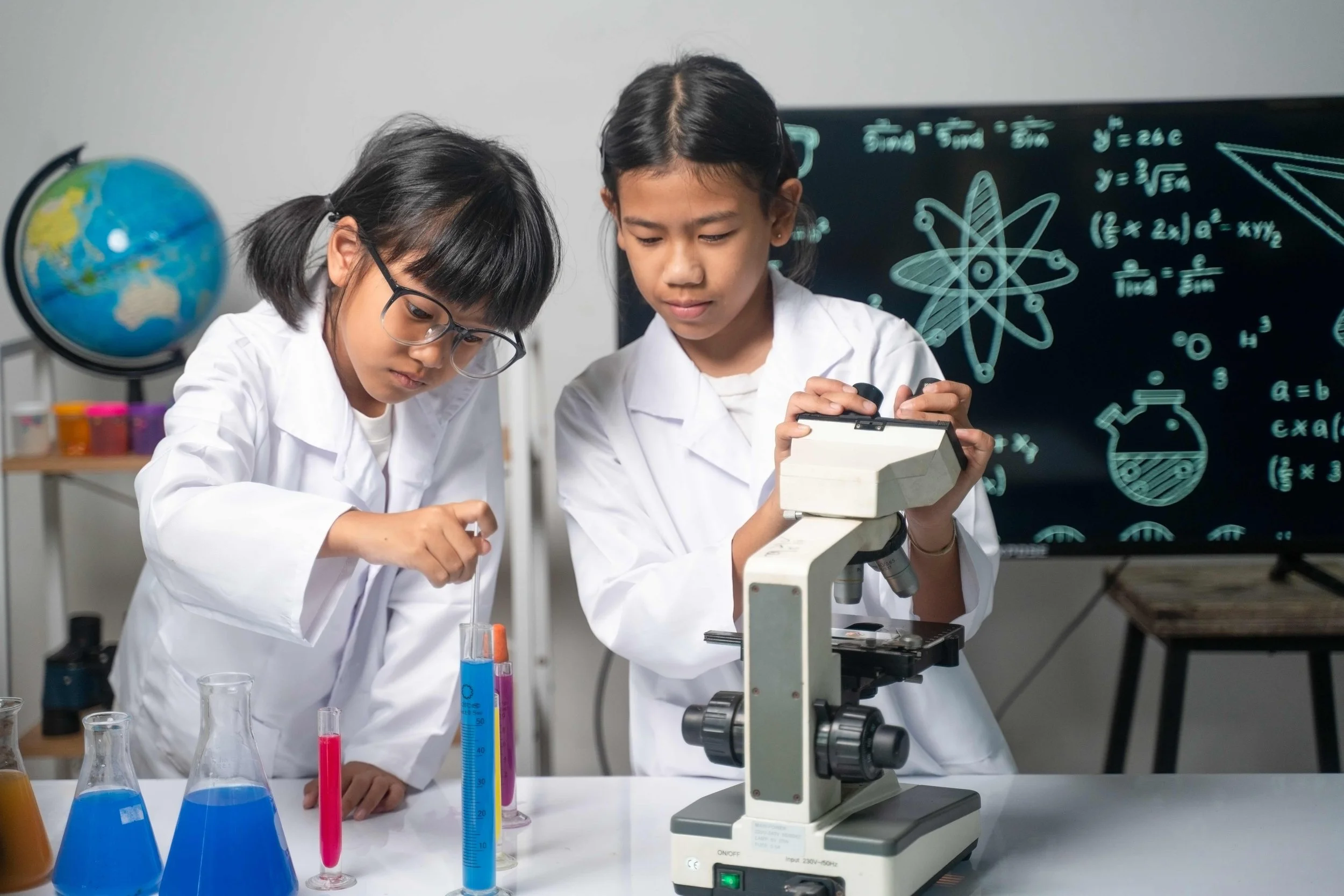 Two young girls in lab coats conducting science experiments