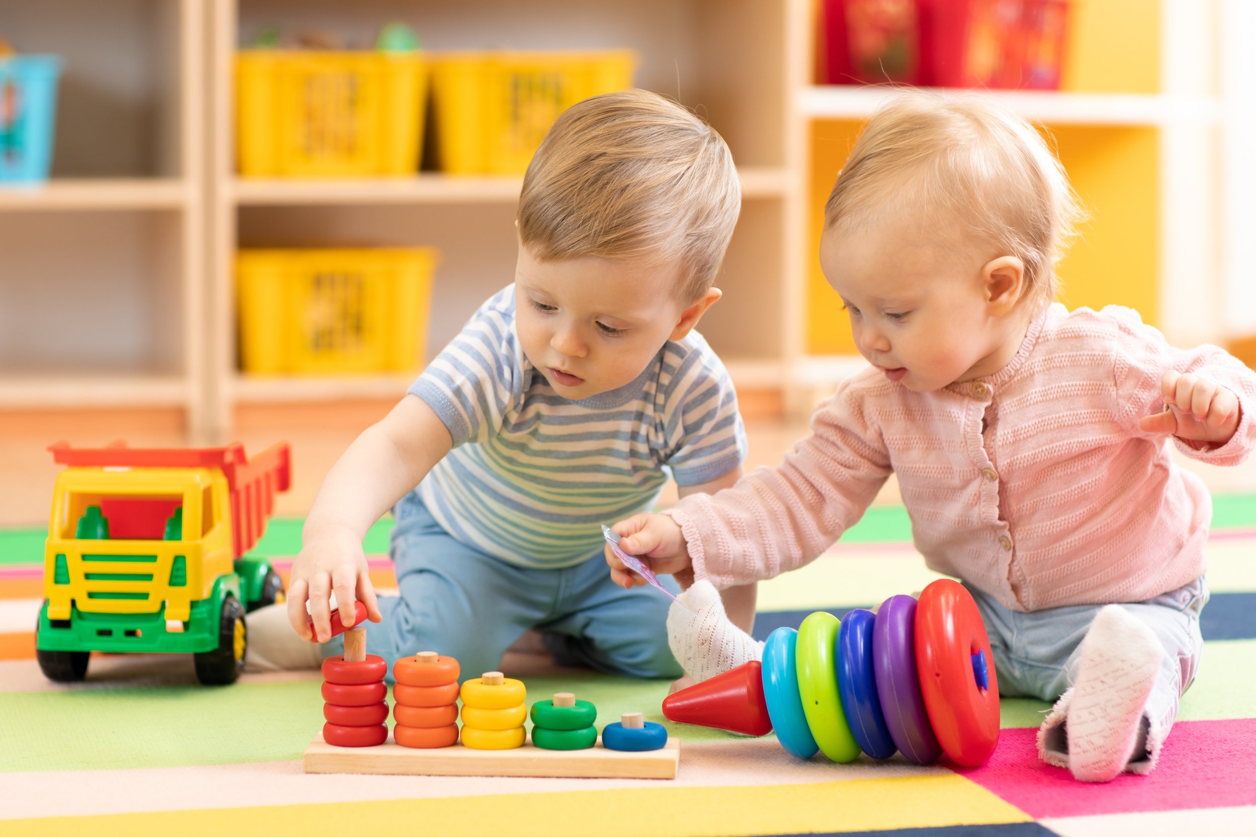 toddlers playing together with stacking toys