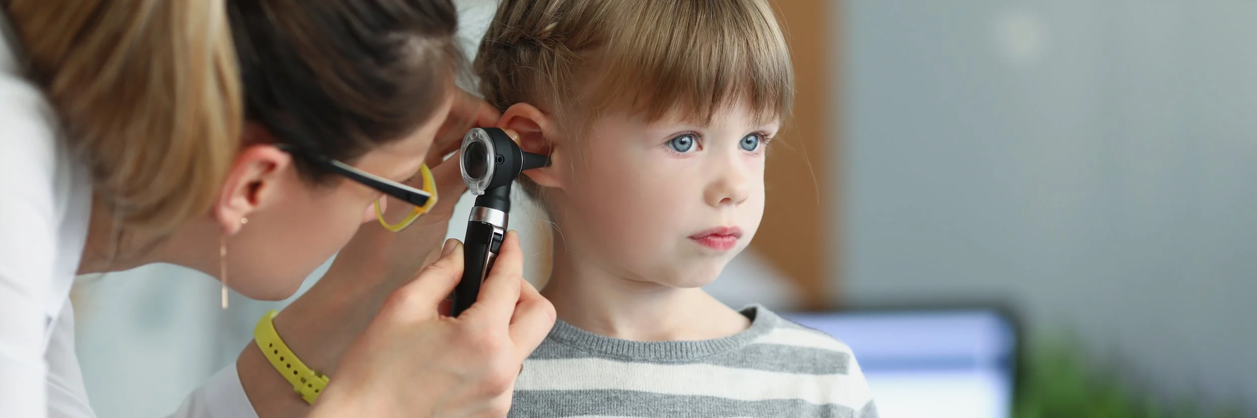 Doctor using an otoscope to look in the ears of a child