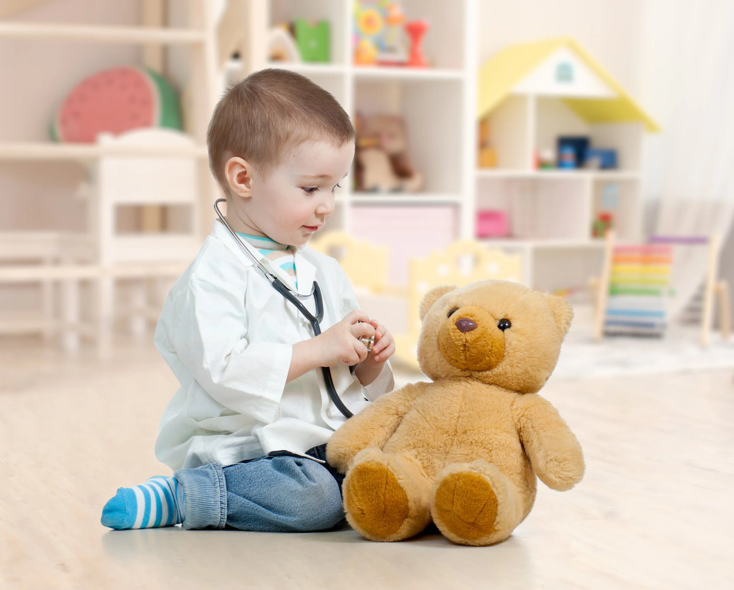 Child playing doctor using a stethoscopr on a teddy bear