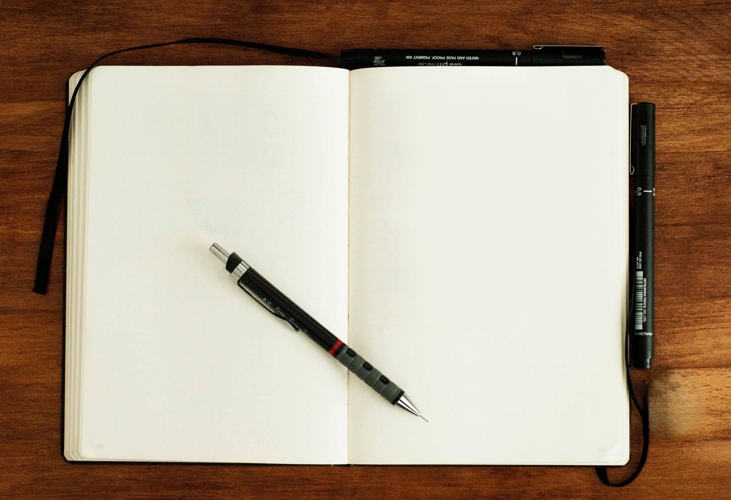 Overhead view of an open blank notebook and pen on a wooden desk, symbolizing the clarity and fresh start of a new financial plan.