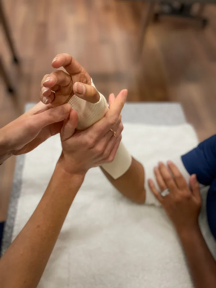 Therapist supporting a bandaged hand during rehabilitation