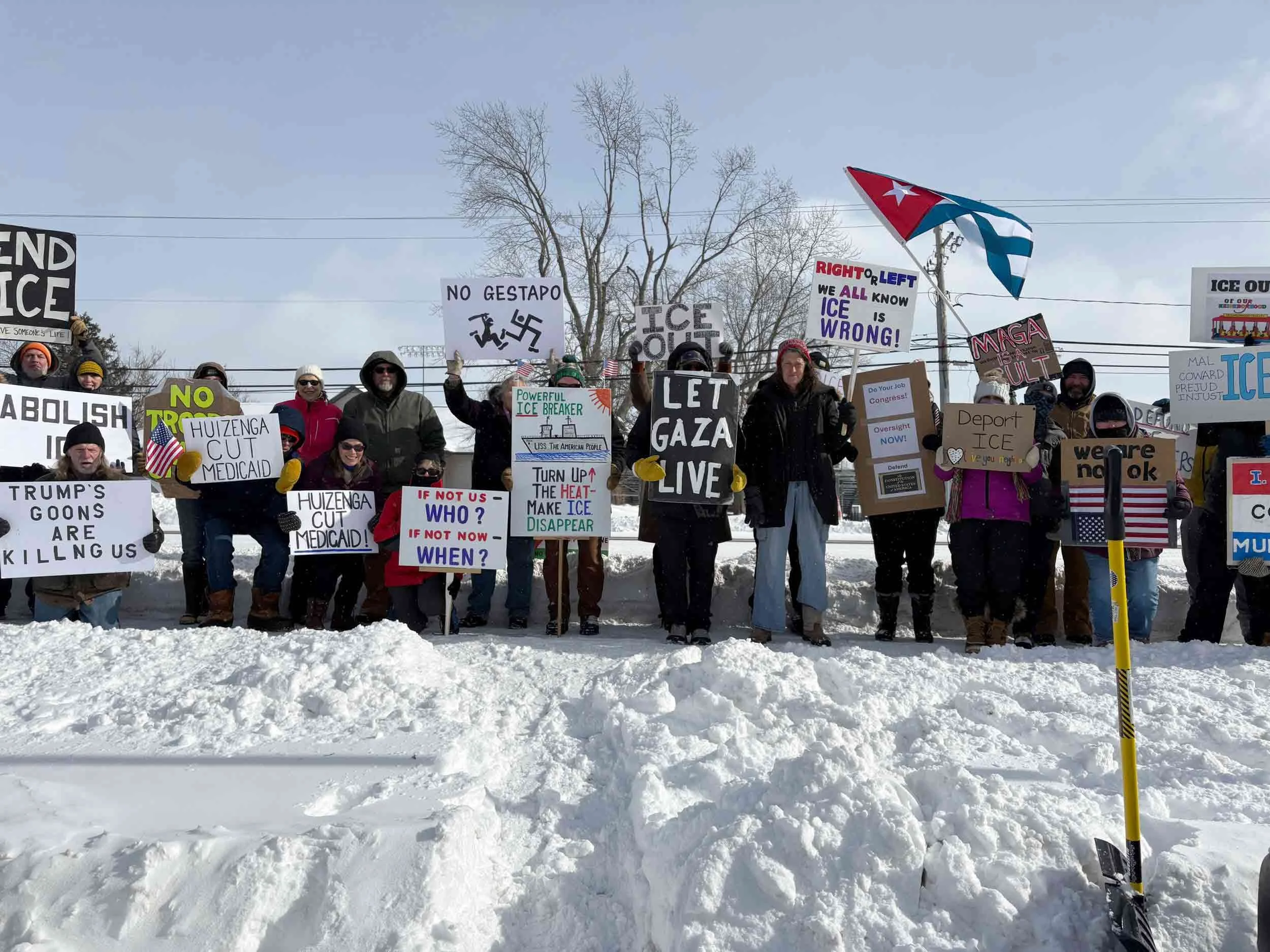 A line of protestors standing in the snow, holding signs.