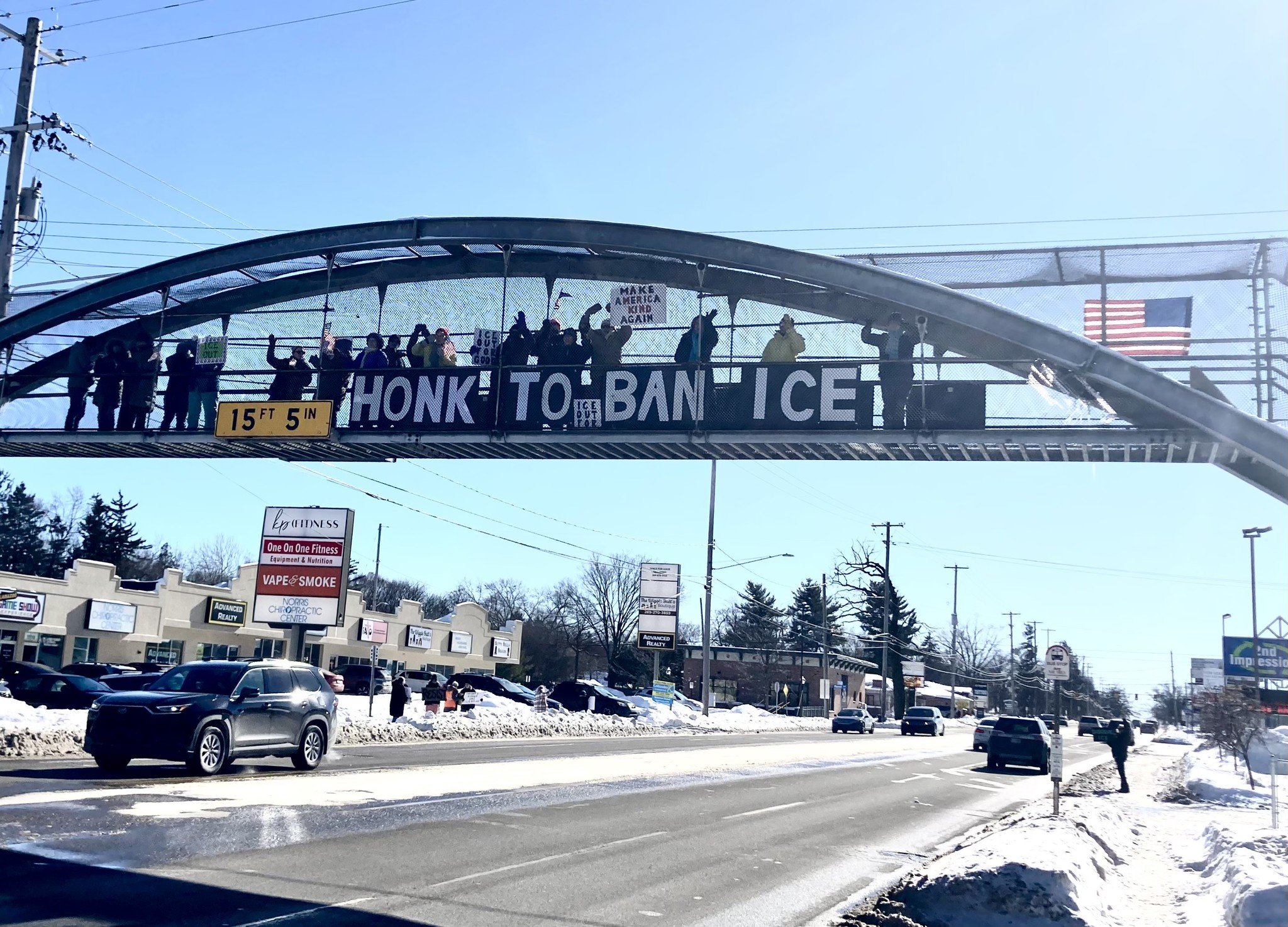 Photo of a bridge with a banner that reads, "Honk to ban ICE".