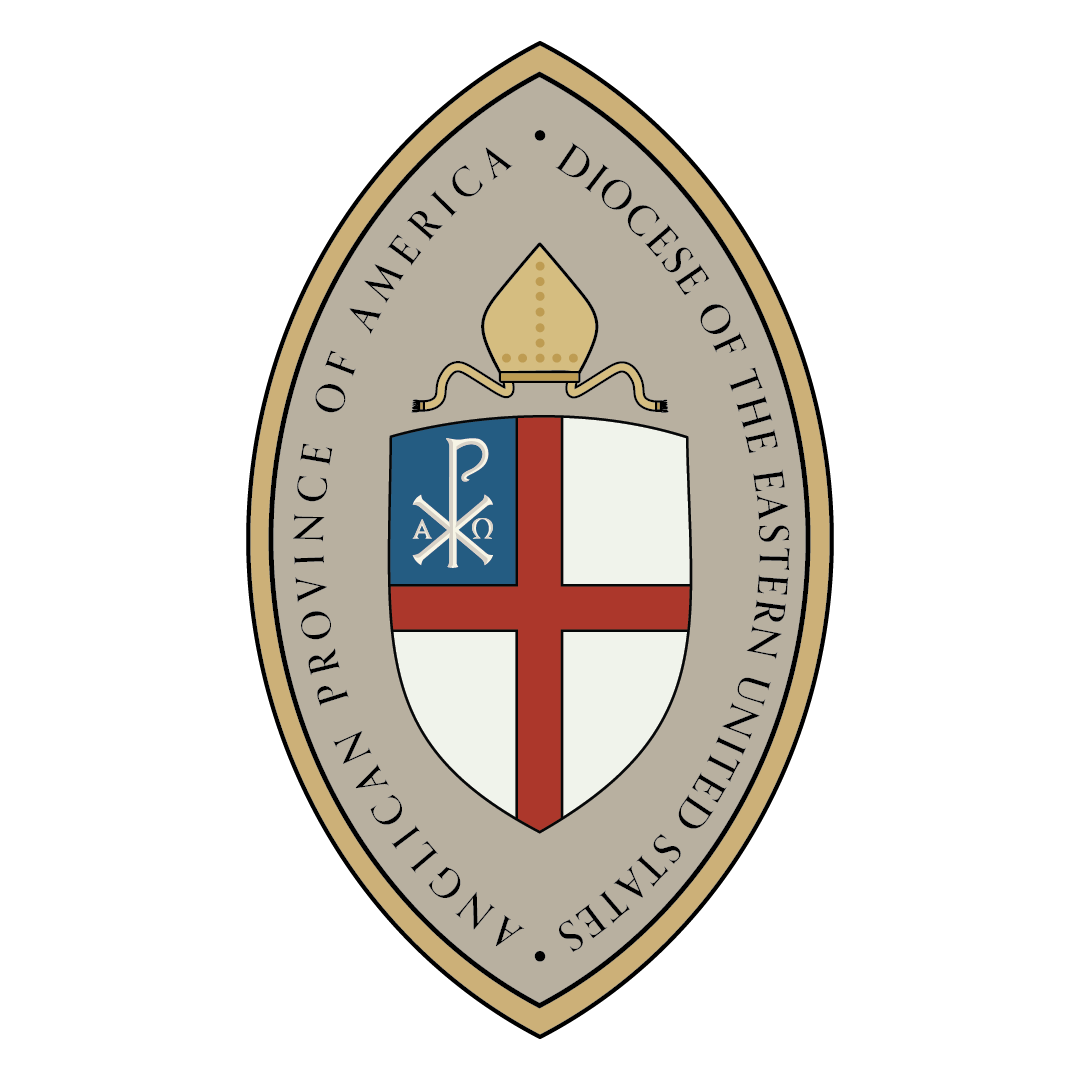 Seal of the Archdiocese of the Eastern United States, featuring a shield with a red cross, a white background, a blue field with a Chi Rho symbol, topped with a gold mitre and enclosed by a ribbon with an inscription.