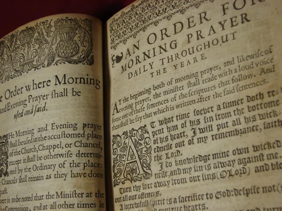 Open old prayer book with ornate decorative borders, large initial letter, and traditional typeface, focusing on morning prayer and order.