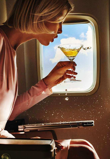Woman holding a martini glass with yellow cocktail on airplane