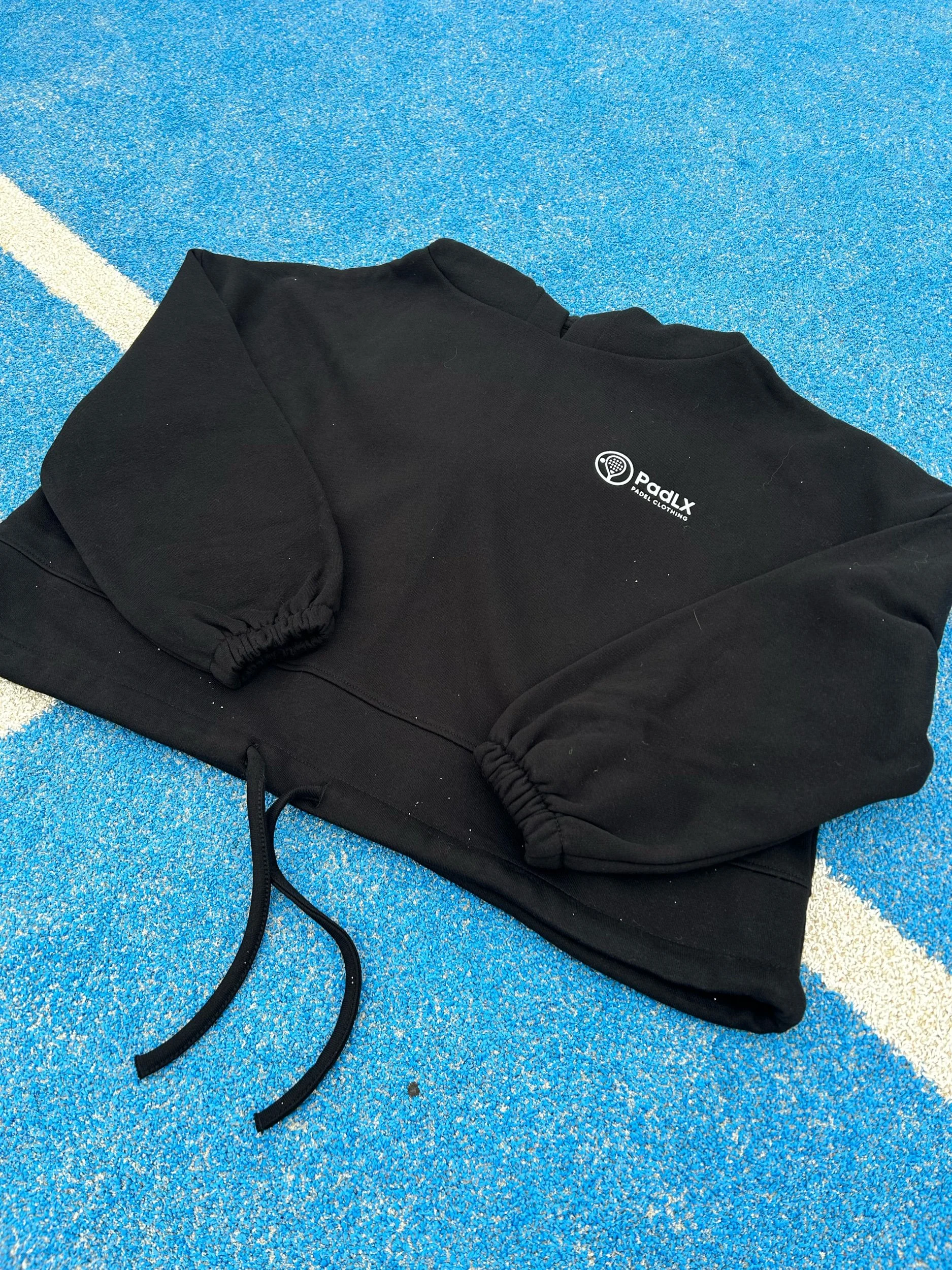 PadLX women’s cropped hoodie laid out on a padel court