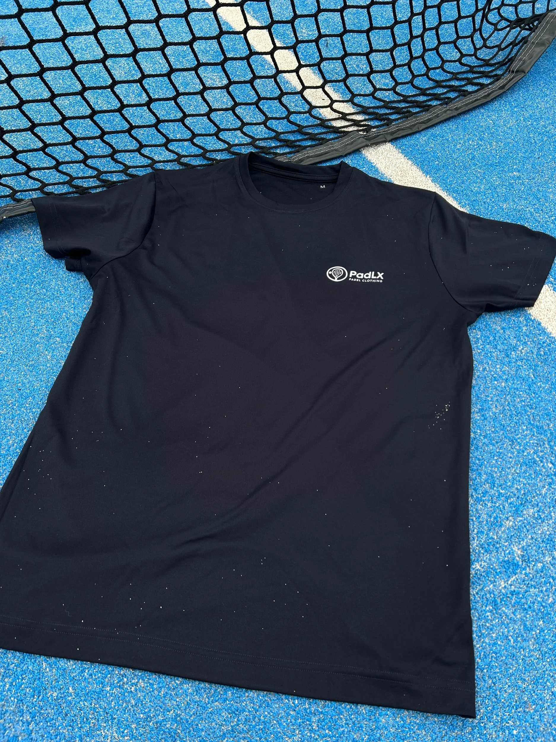 PadLX performance t-shirt laid on a padel court