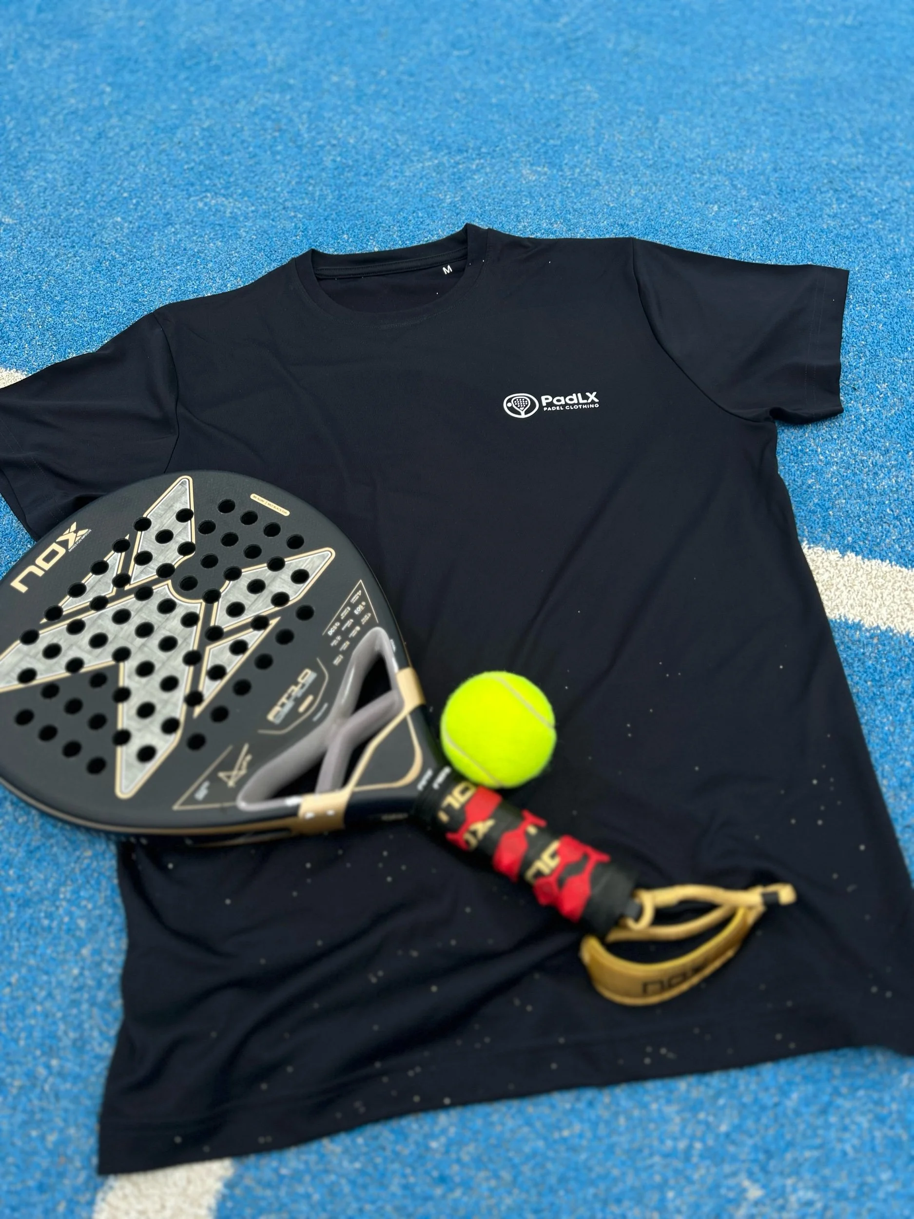 PadLX performance t-shirt laid on a padel court with racket and ball