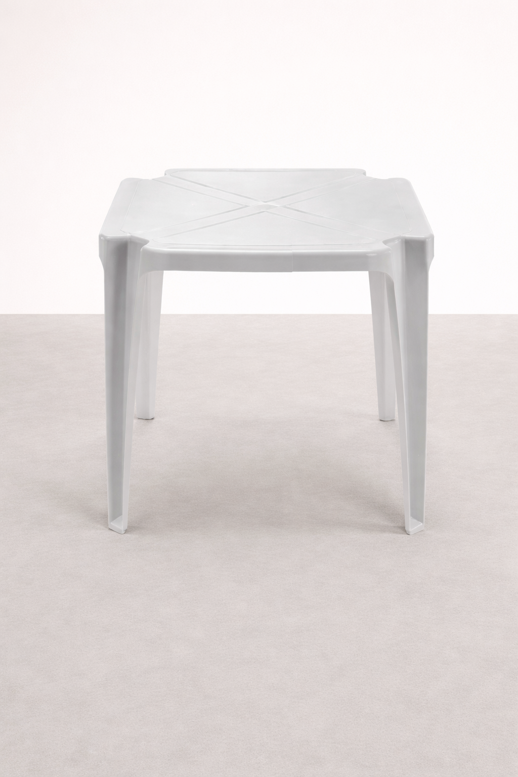 Mesa de plástico branca com design simples, localizada em um ambiente com paredes brancas e piso claro.