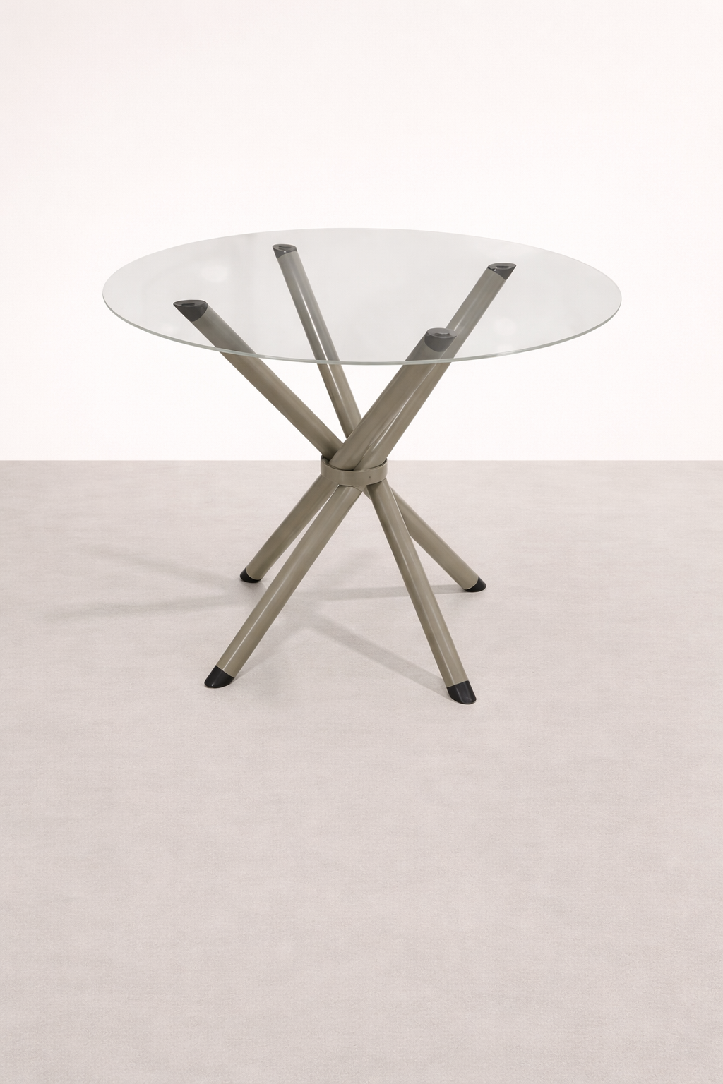 Mesa de vidro redonda com pernas de metal cinza, apoiada no chão