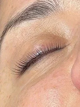 Close-up of a closed eye with natural makeup, showing long eyelashes and well-groomed eyebrow.